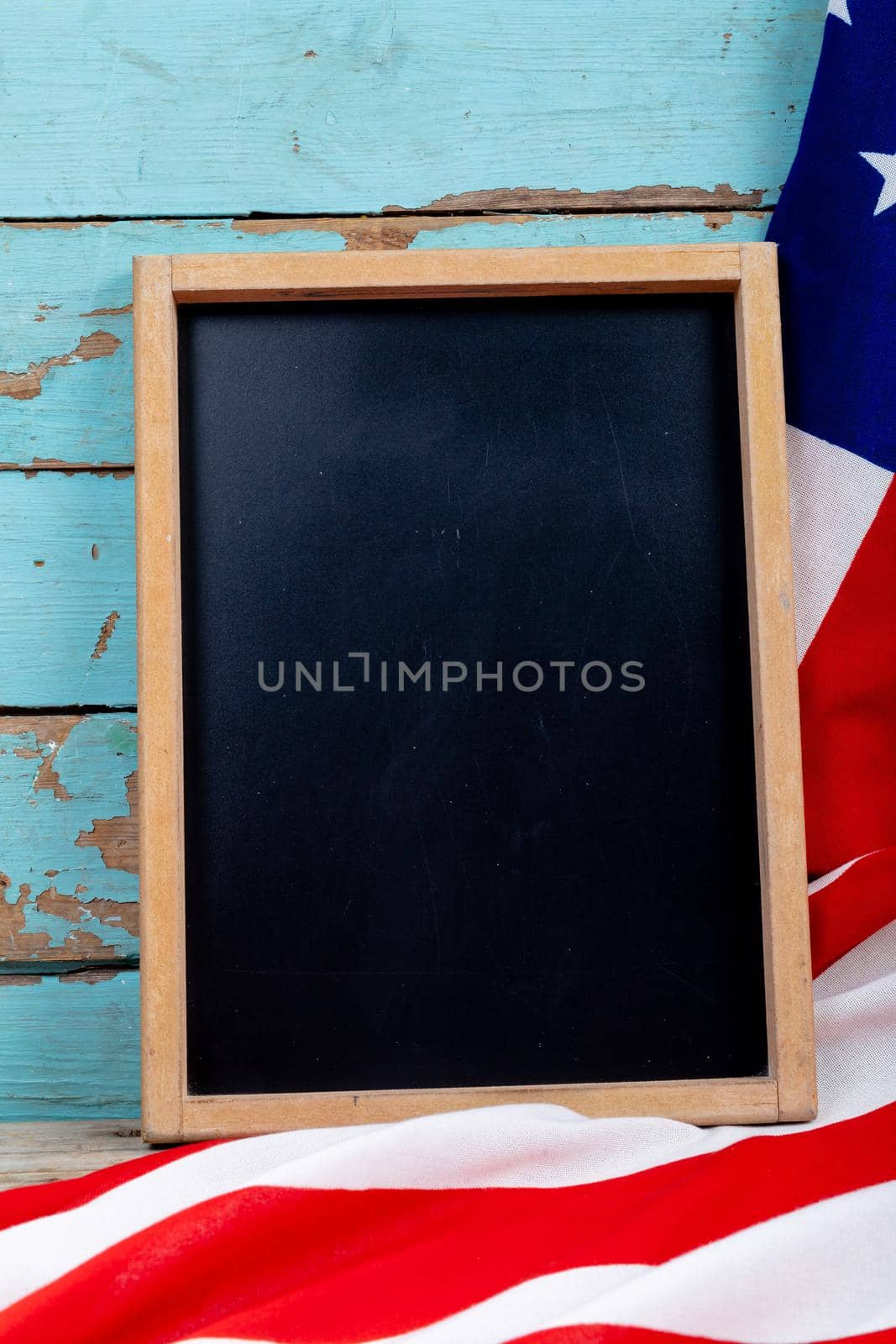 Overhead view of blank writing slate with copy space by usa flag on blue wooden table. patriotism, symbol and identity.