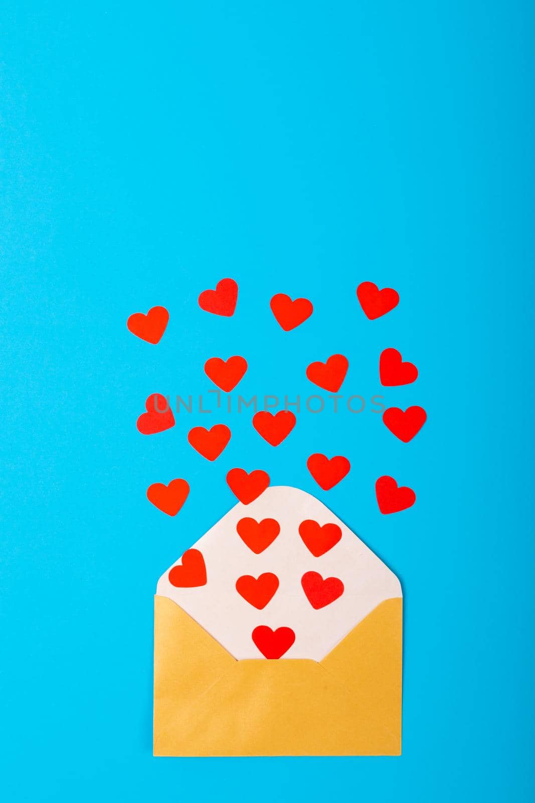 Overhead view of red hearts coming out from yellow envelope over blue background, copy space. valentine's day and love concept.