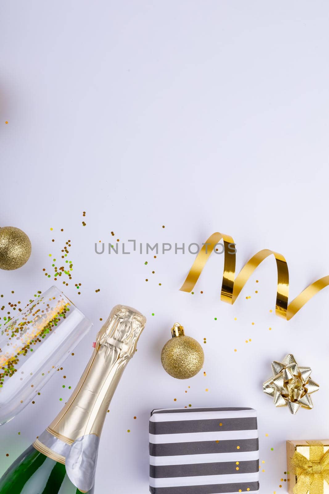 Overhead shot of christmas gifts and decoration by champagne on white background, copy space. celebration, party and christmas concept.