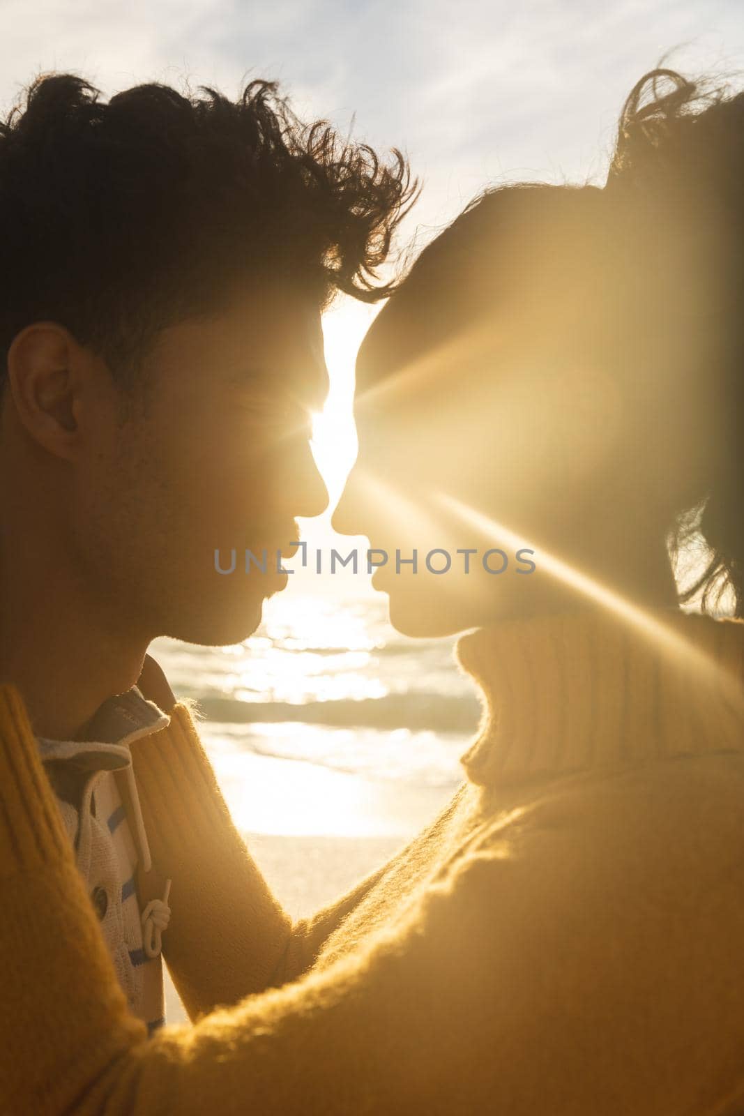 Back lit biracial couple face to face romancing at beach during sunset by Wavebreakmedia
