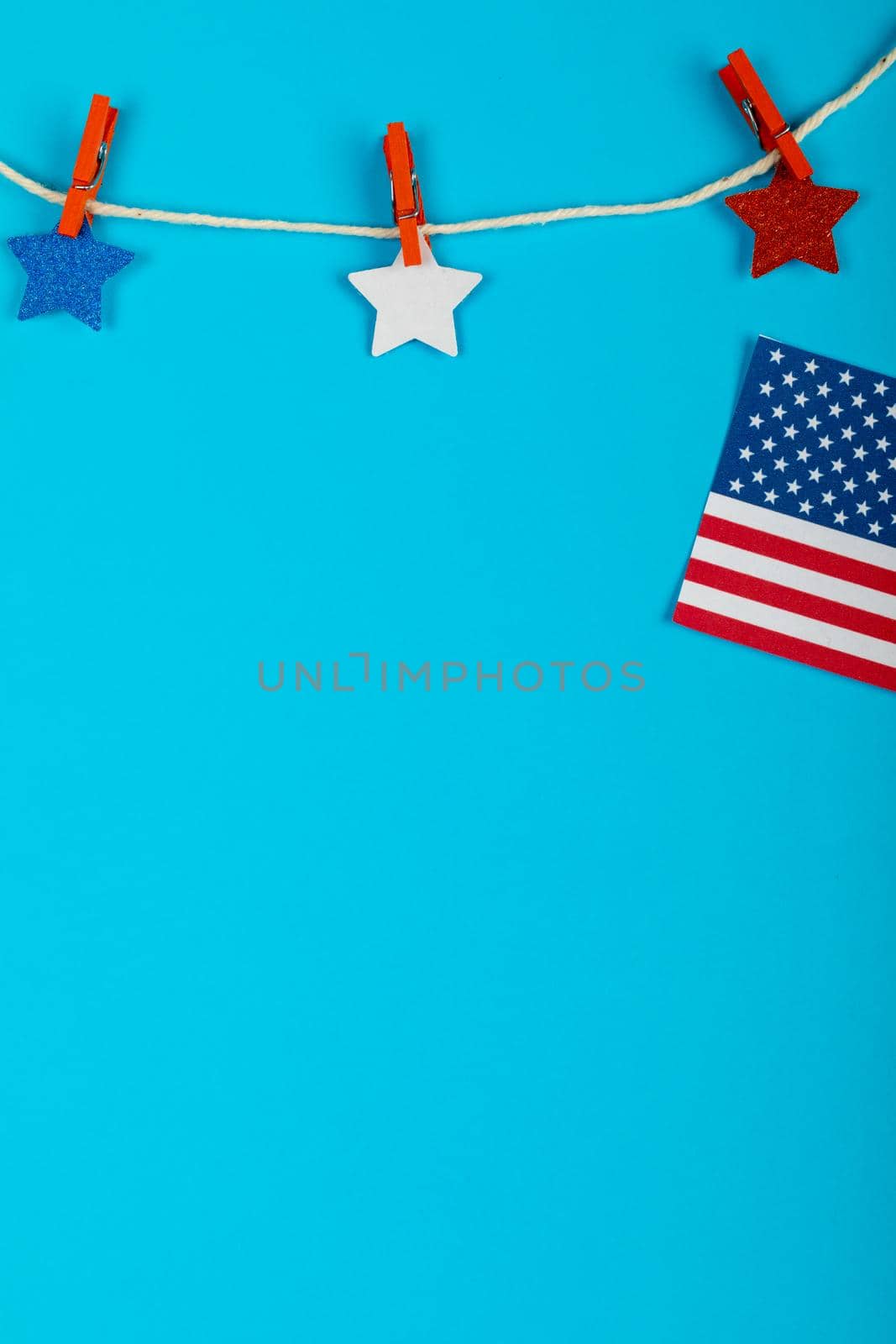Clothespins holding star shapes on string by usa flag with copy space on blue background. patriotism and identity.