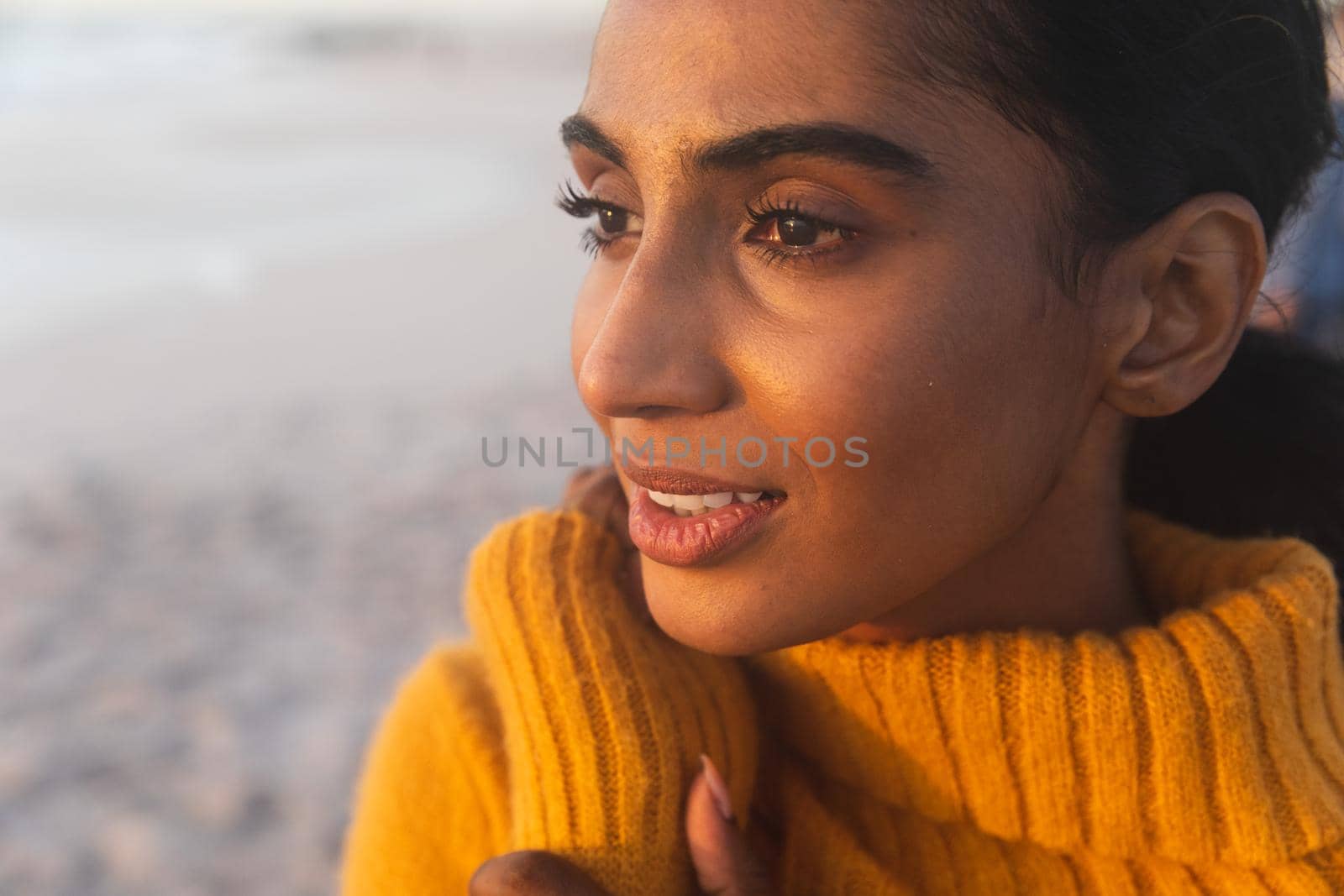 Close-up of young biracial woman thinking while looking away at beach during sunset by Wavebreakmedia