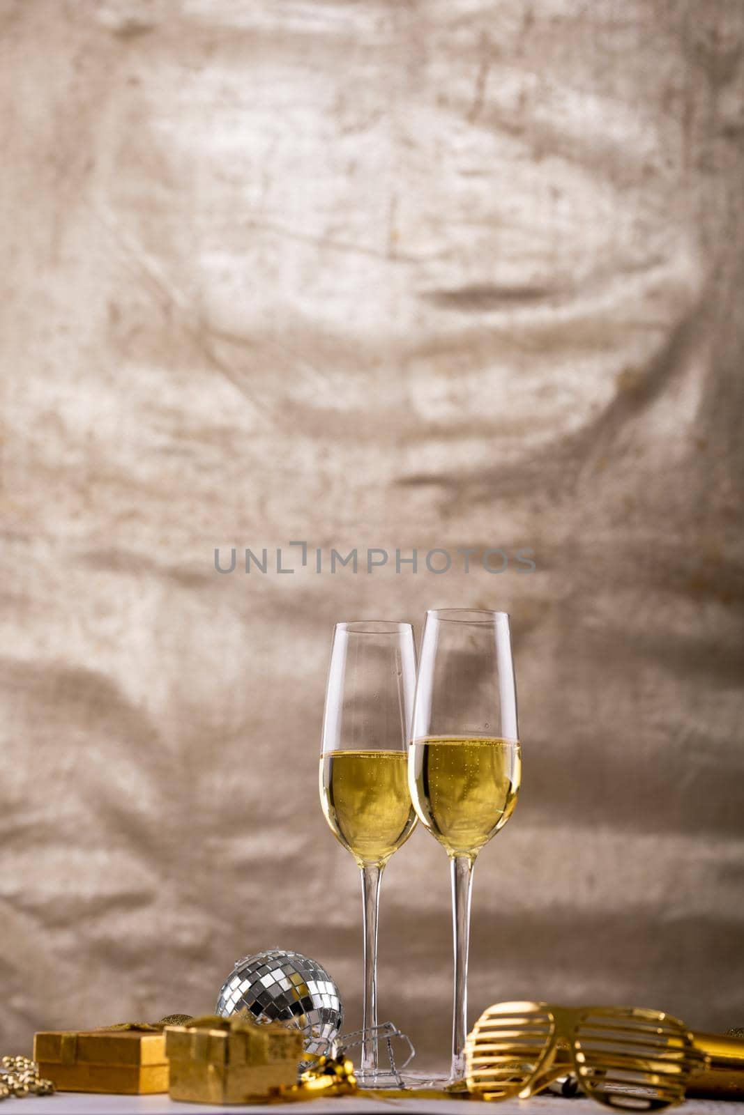 Champagne flutes with decoration and gift boxes over beige backdrop, copy space by Wavebreakmedia