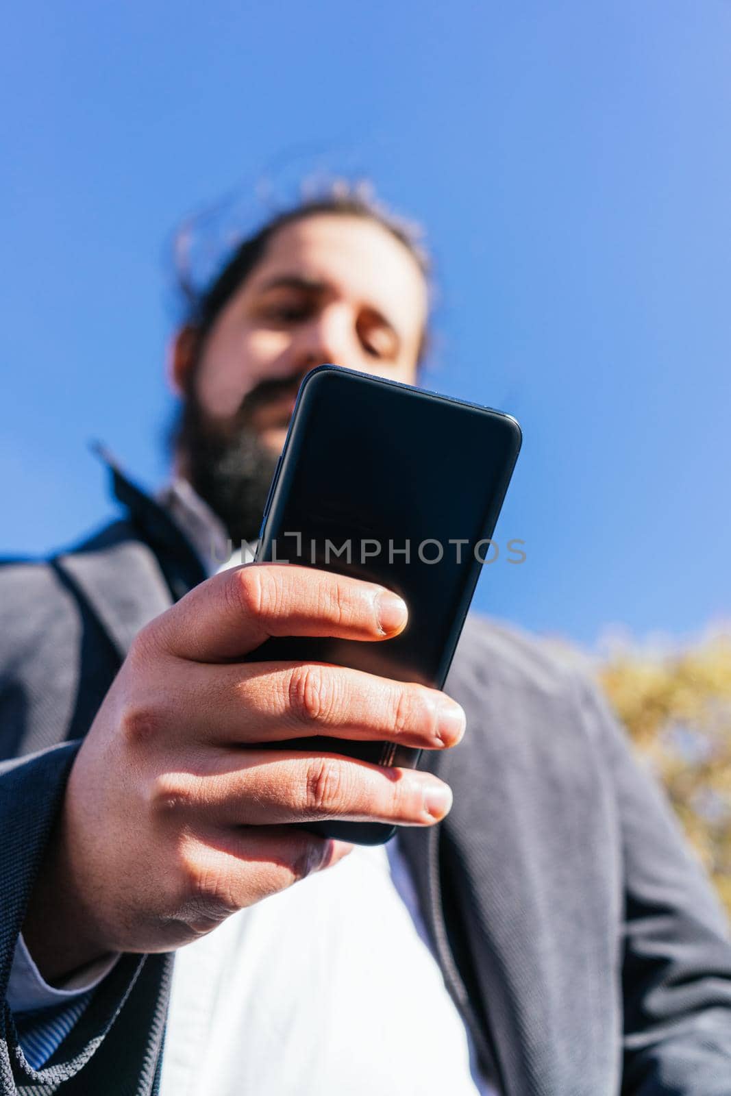 young business man looking phone near to office. Natural light in a sunny day.