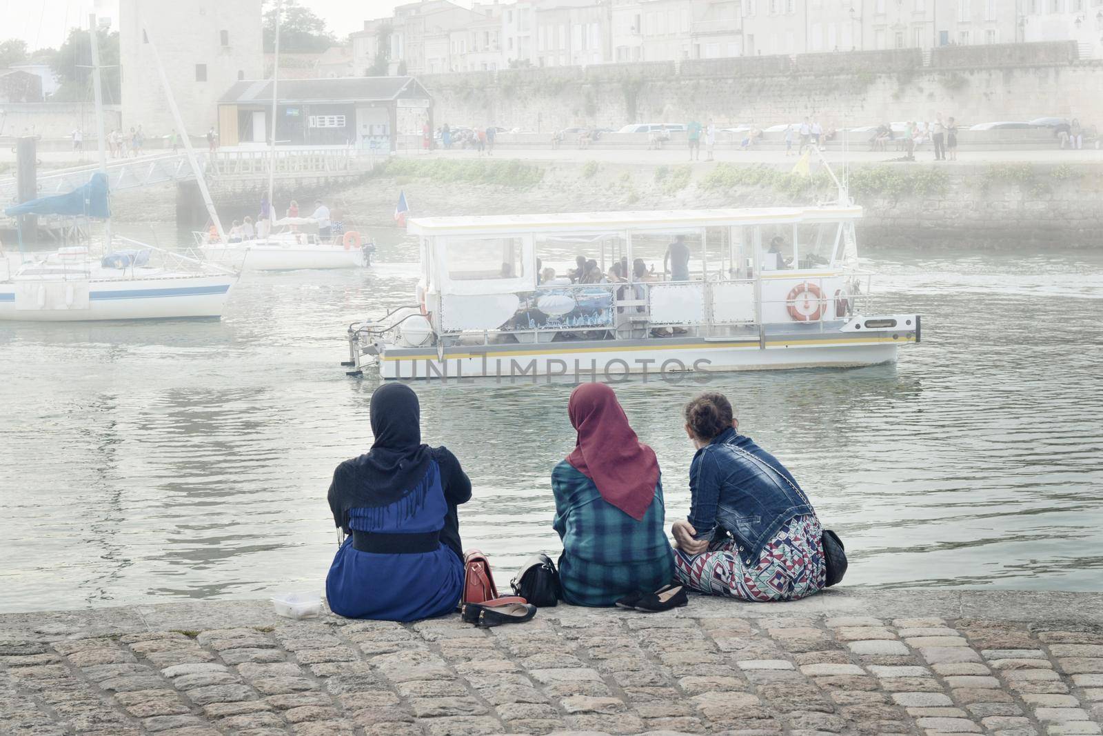 LA ROCHELLE, FRANCE - AUGUST 12, 2015: Muslim woman wearing hijab looking on the ocean Atlantic and yachts at La Rochelle, France.