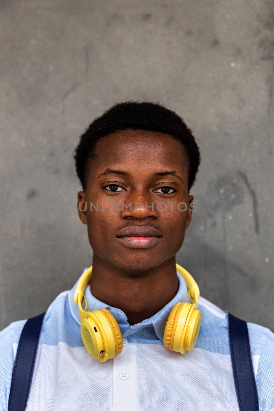 Vertical portrait of teen African American male high school student looking at camera. by Hoverstock