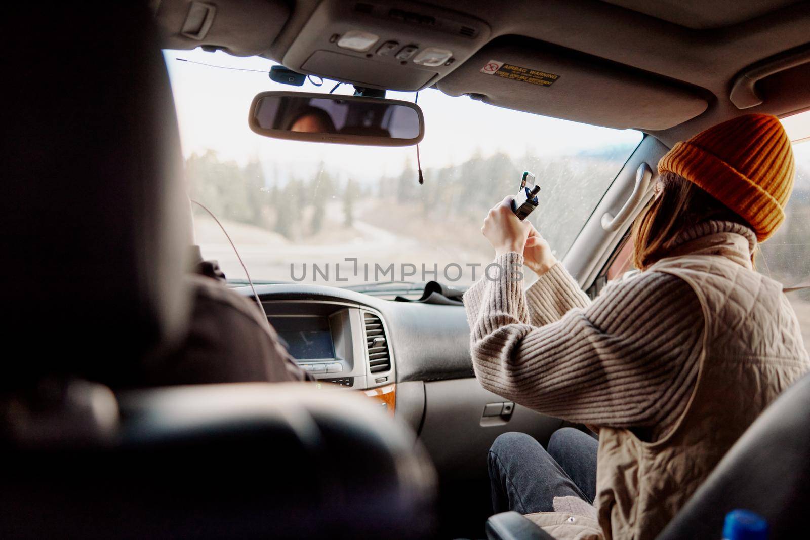 woman in a hat with a phone in her hands shoots a video of nature in a car. High quality photo