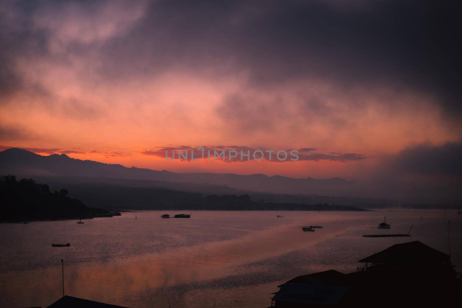 Scenery of sunrise over beautiful lake with warm sky and sunlight reflected water ripple on a winter morning. by TEERASAK