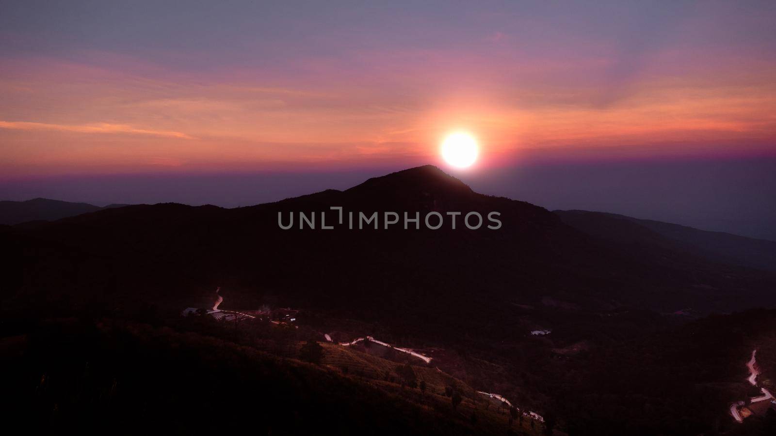 Beautiful landscape silhouette on the mountain peak during sunset with warm sunlight and dramatic sky. by TEERASAK