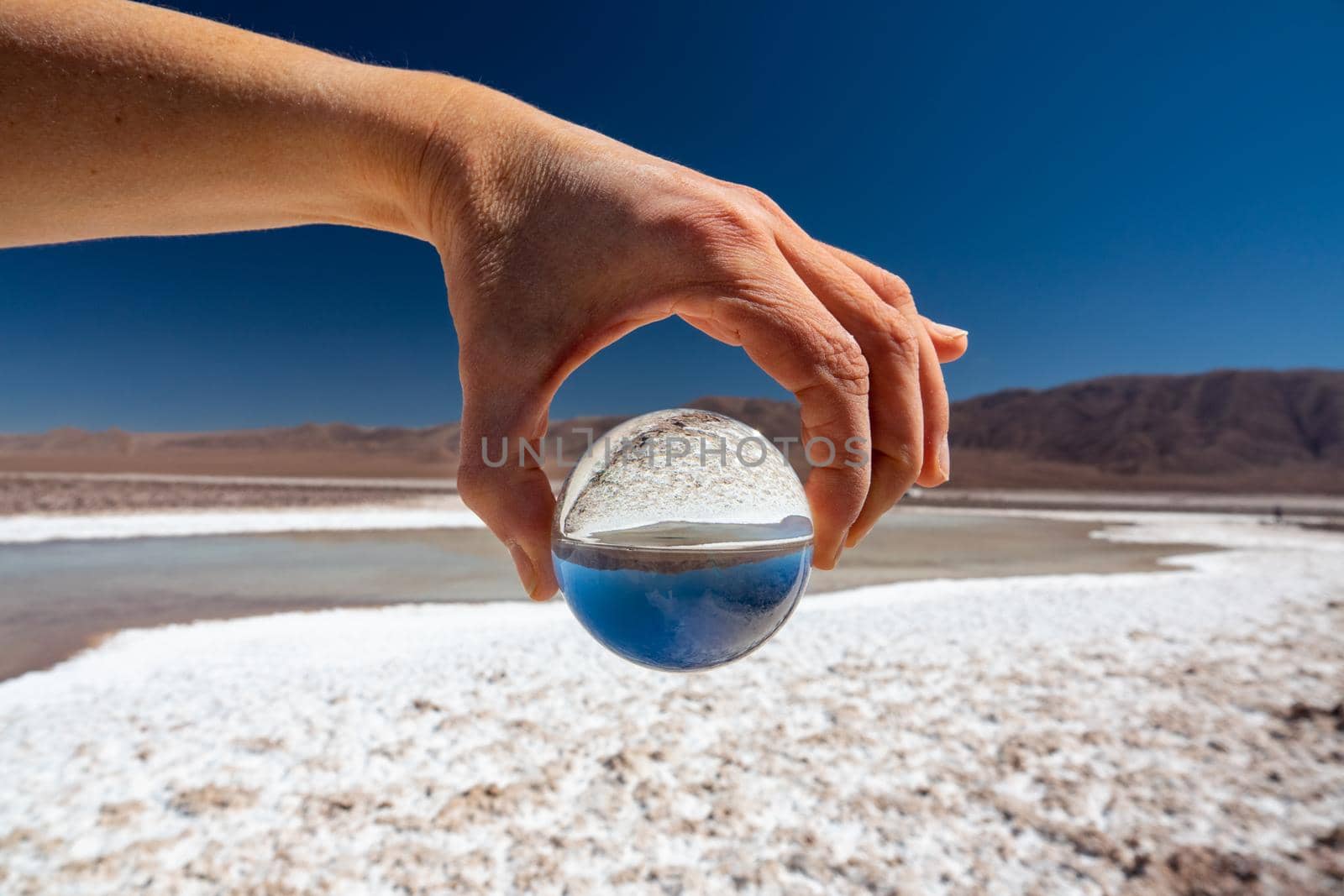 Salted hand holding glass ball at salt lakes in Atacama