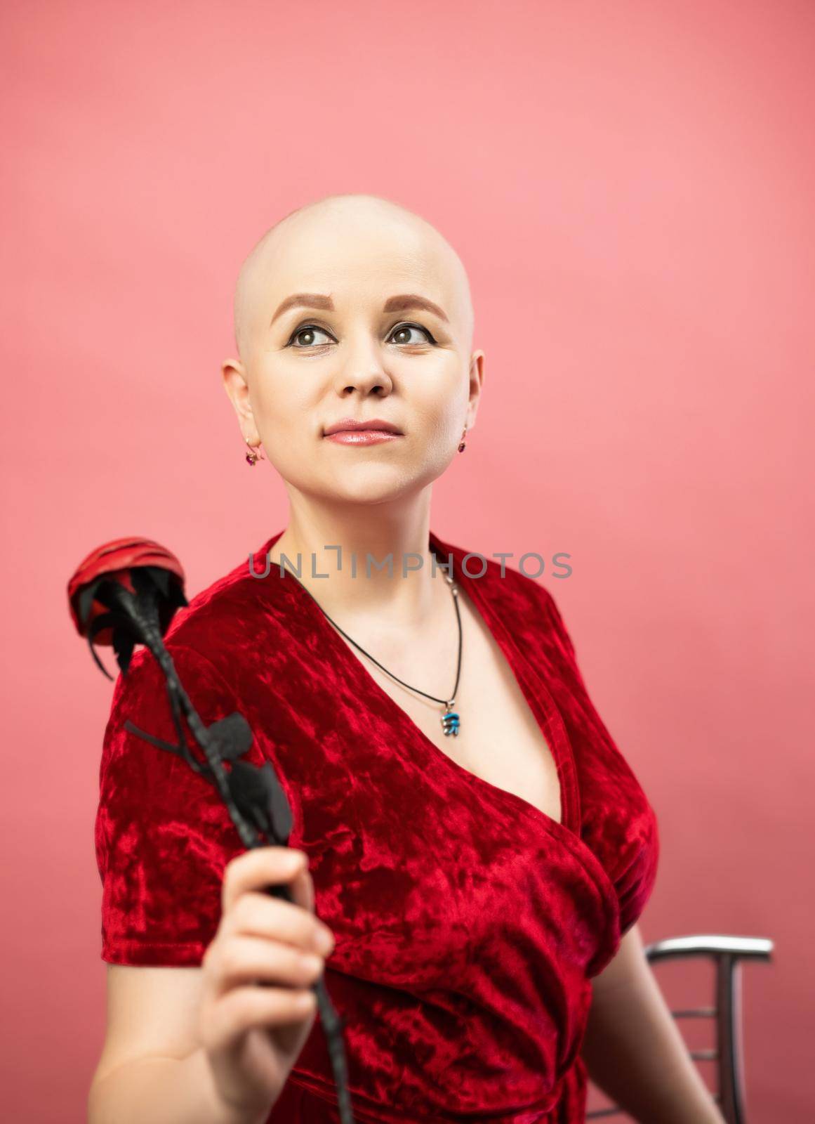 portrait of a bald woman with cancer after chemotherapy in a red robe with an artificial rose flower by Rotozey