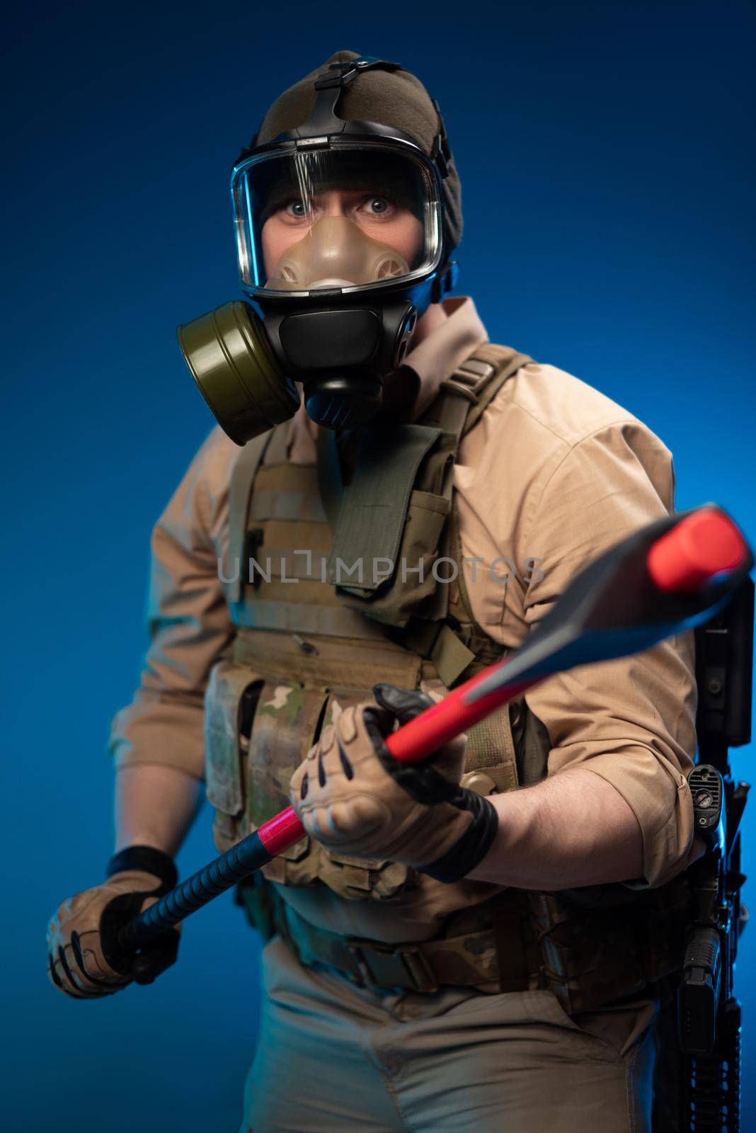 a soldier in military clothes with a bulletproof vest in a gas mask is holding a red fire axe in his hands in fright by Rotozey