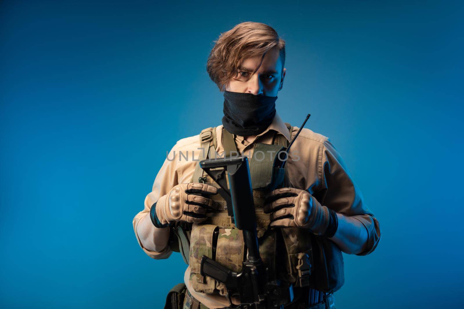 a male special agent soldier in a bulletproof vest with an automatic rifle on a blue background by Rotozey