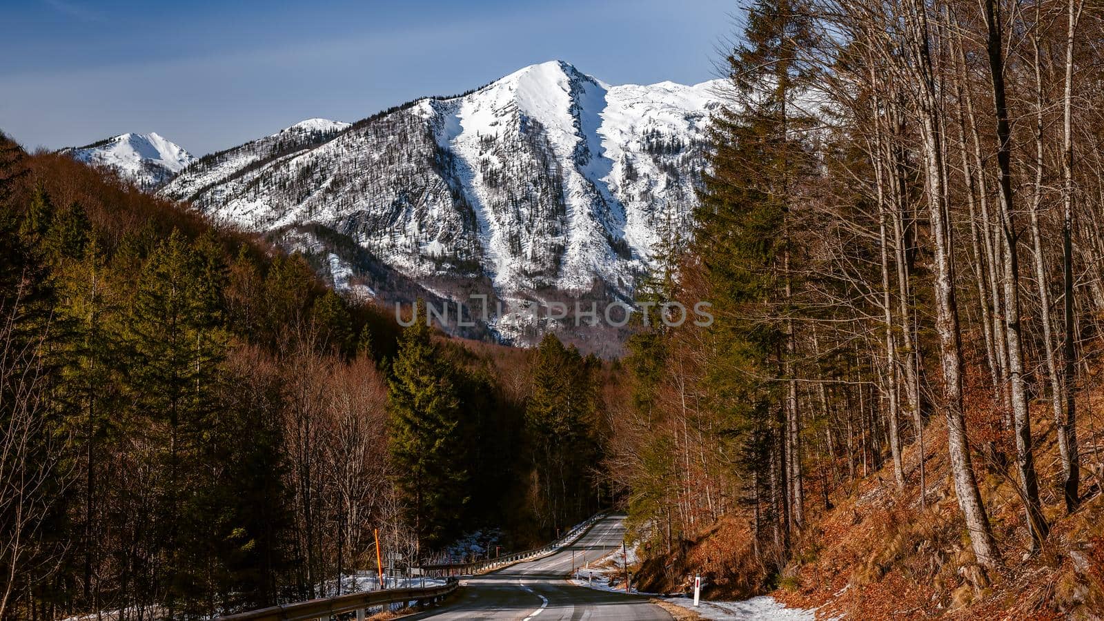 Winter mountains and a road in Austrian Alps, alpine forest landscape