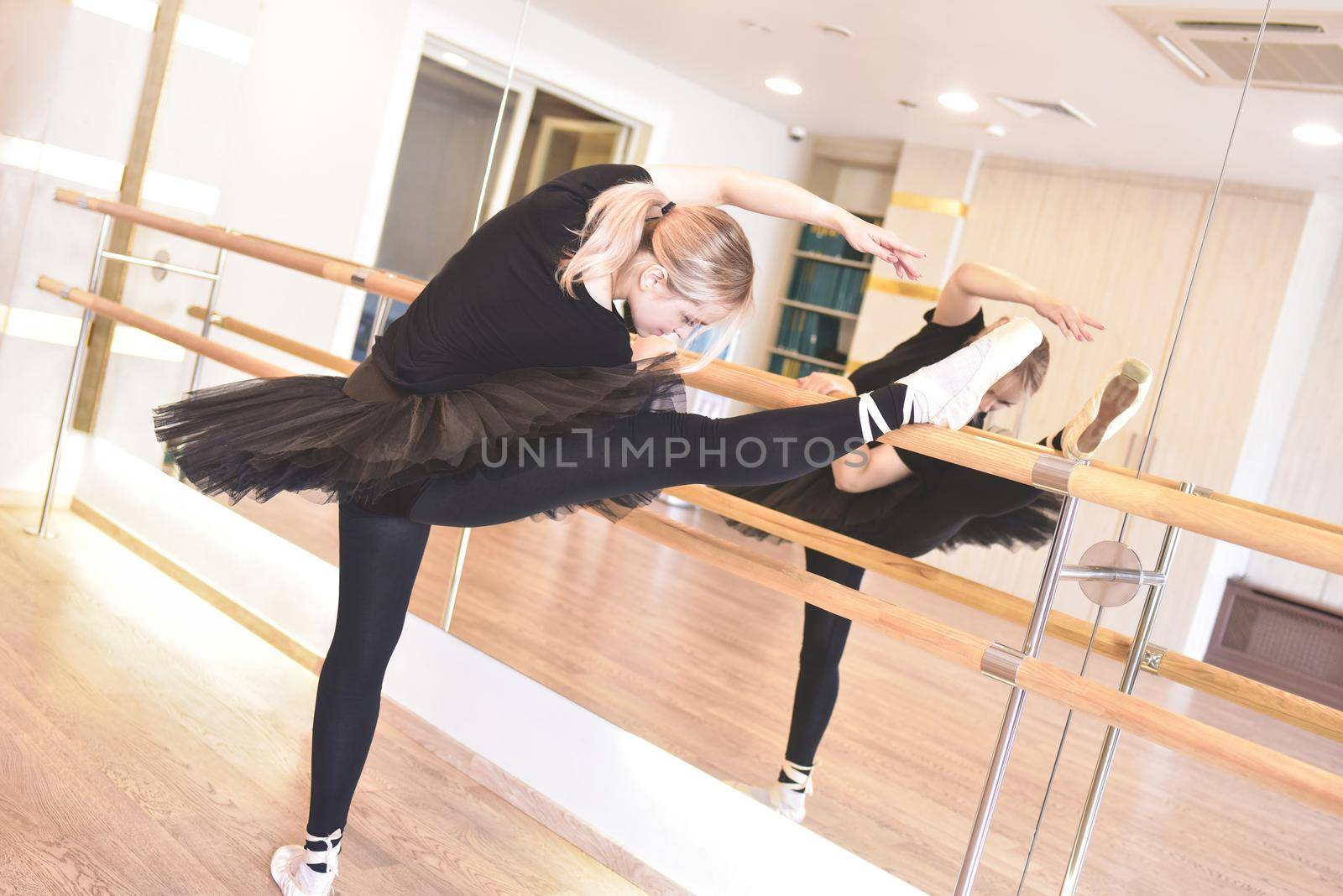 ballerina in black wear is practicing in the dance studio by Nickstock