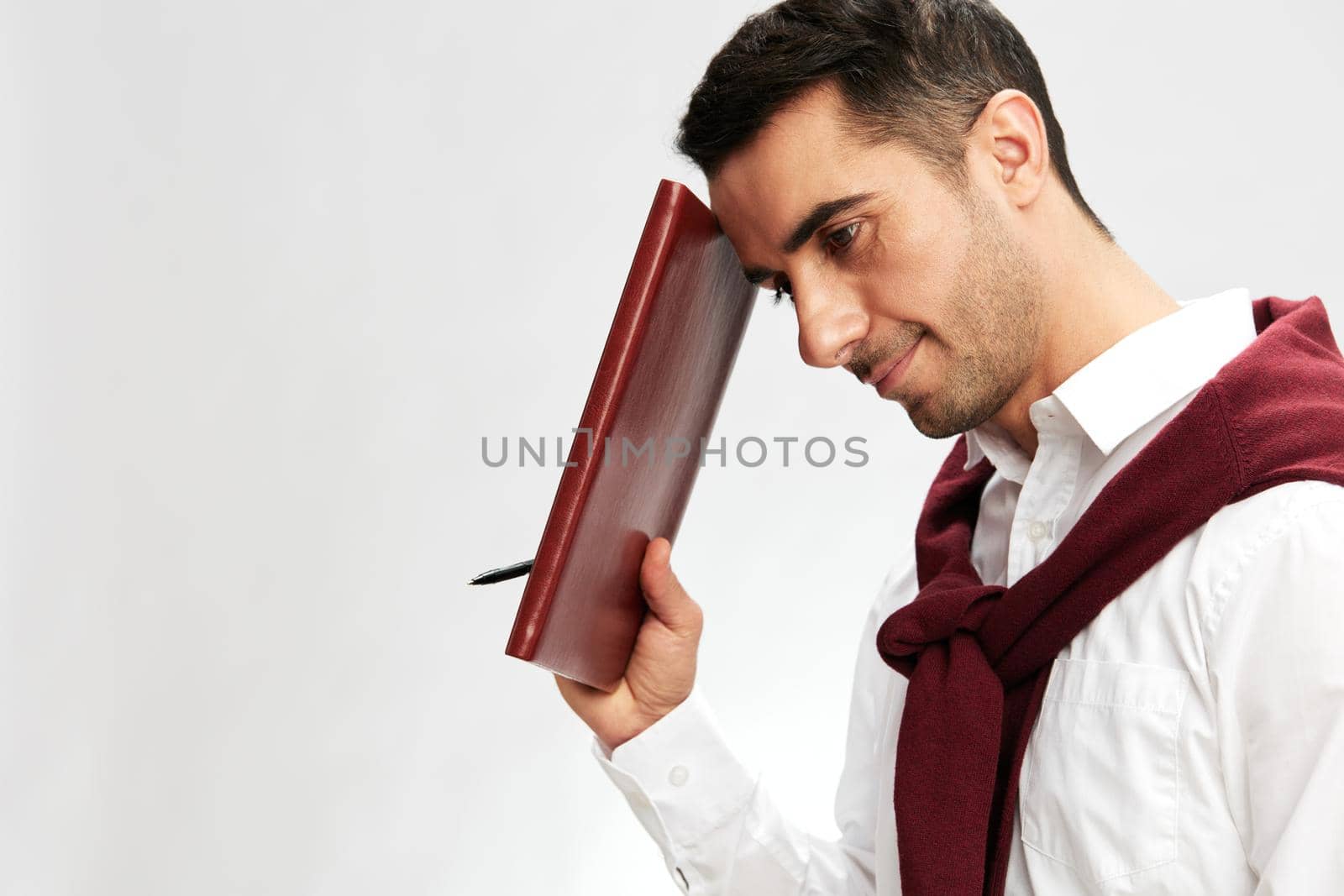 handsome man in a white shirt sweater on the shoulders notebook posing isolated background by SHOTPRIME