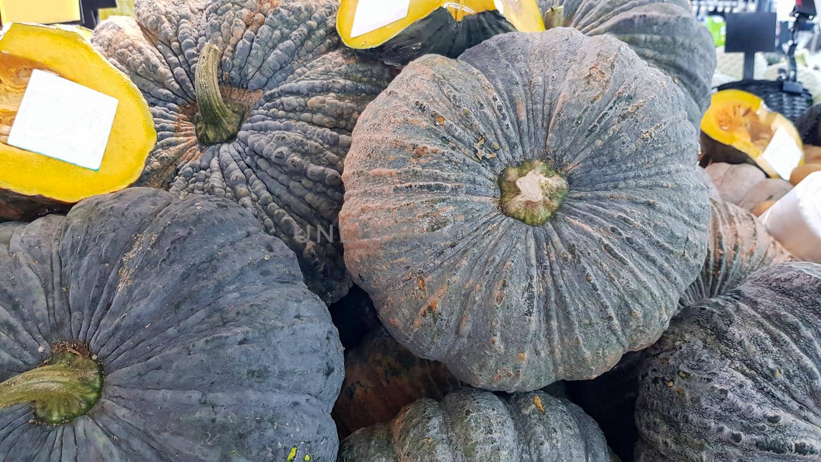 Several pumpkins were placed on the shelf. Some pumpkins were cut in half and had a white label attached to them. by pichai25