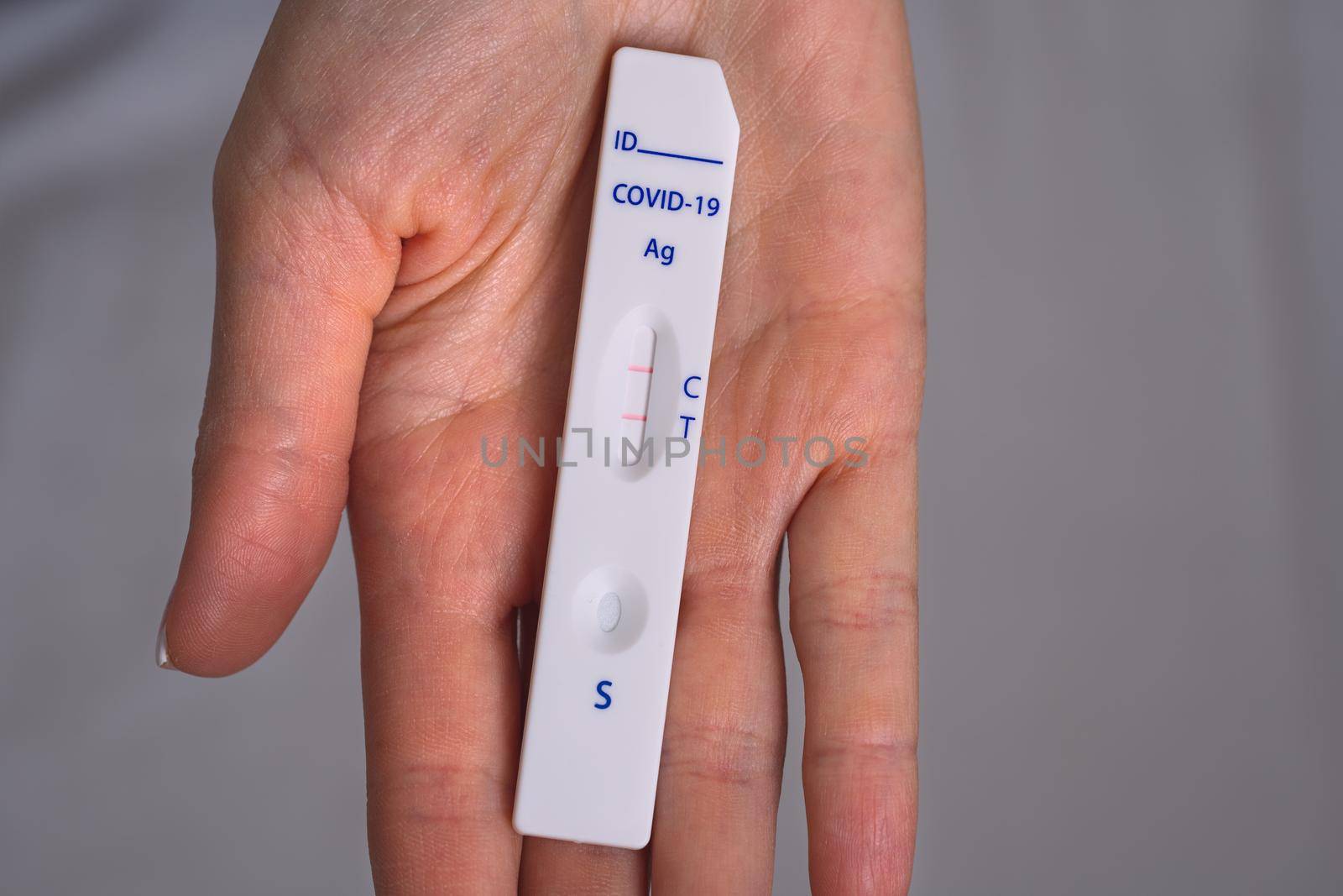 Woman hand holding rapid covid antigen test or express covid test with positive covid-19 result by DariaKulkova