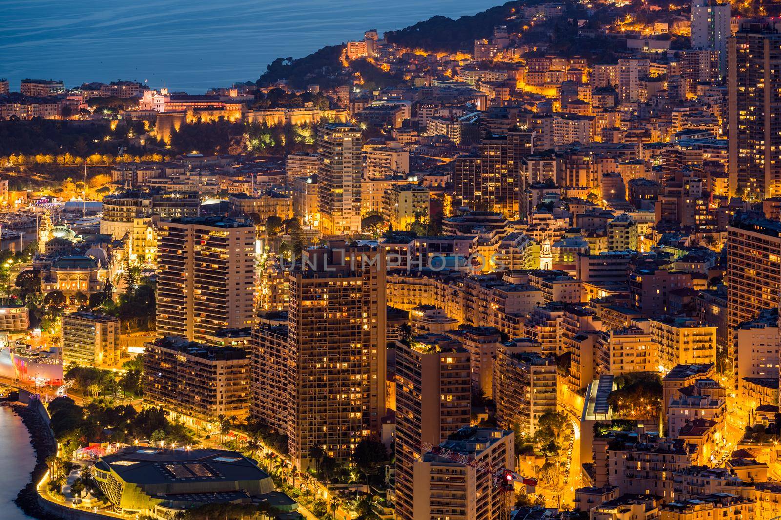 Aerial view of Monaco - Monte-Carlo at dusk, cityscape with night illumination, mountain, skyscrapers, mediterranean sea. High quality photo