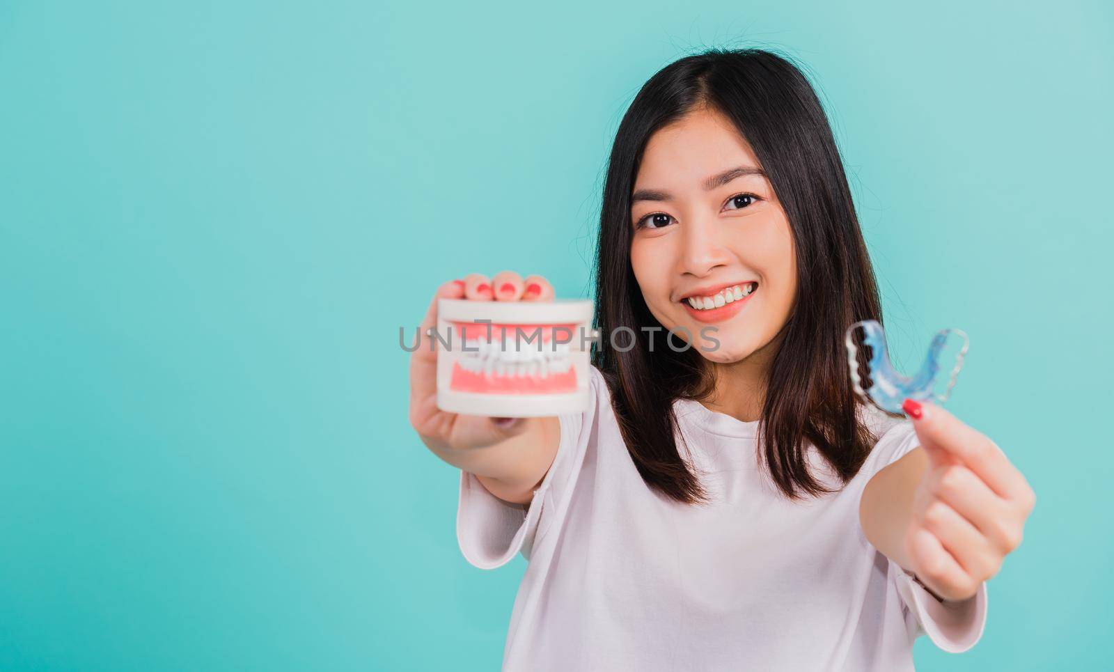 Portrait young Asian beautiful woman smiling holding silicone orthodontic retainers for teeth retaining tools after removable braces, Female hold model teeth before, Orthodontics dental healthy care