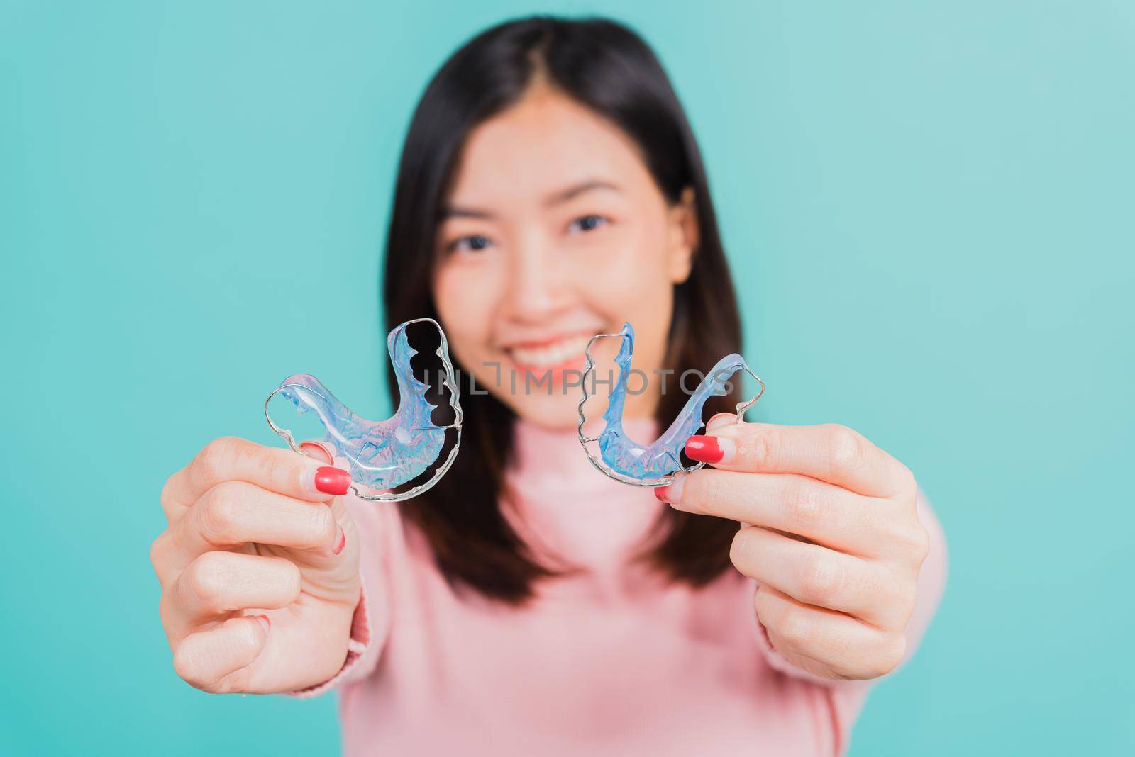 woman smiling hold silicone orthodontic retainers for teeth by Sorapop