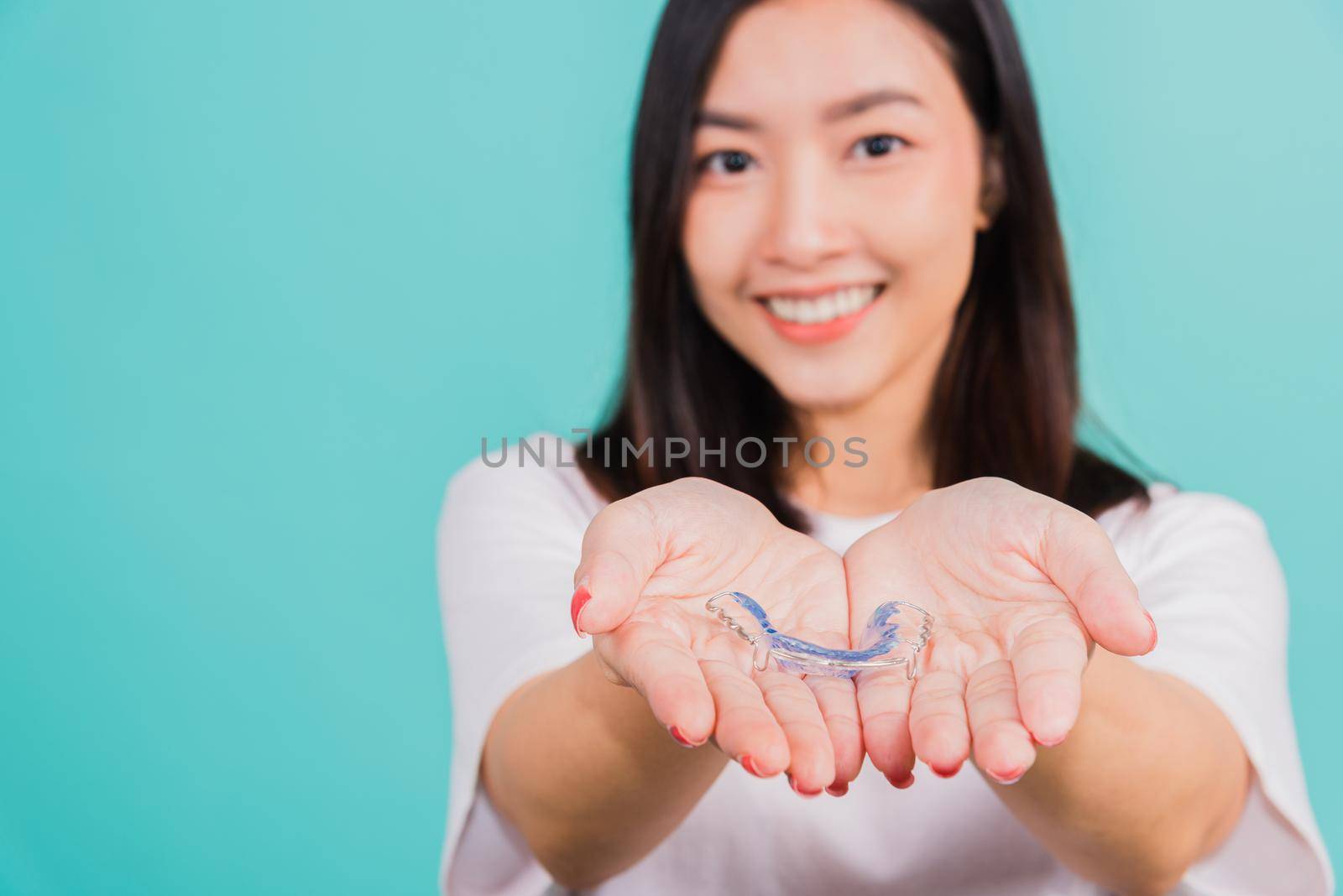 Portrait young Asian beautiful woman smiling holding silicone orthodontic retainers for teeth on hand palm, Teeth retaining tools after removable braces, Orthodontics dental healthy care concept