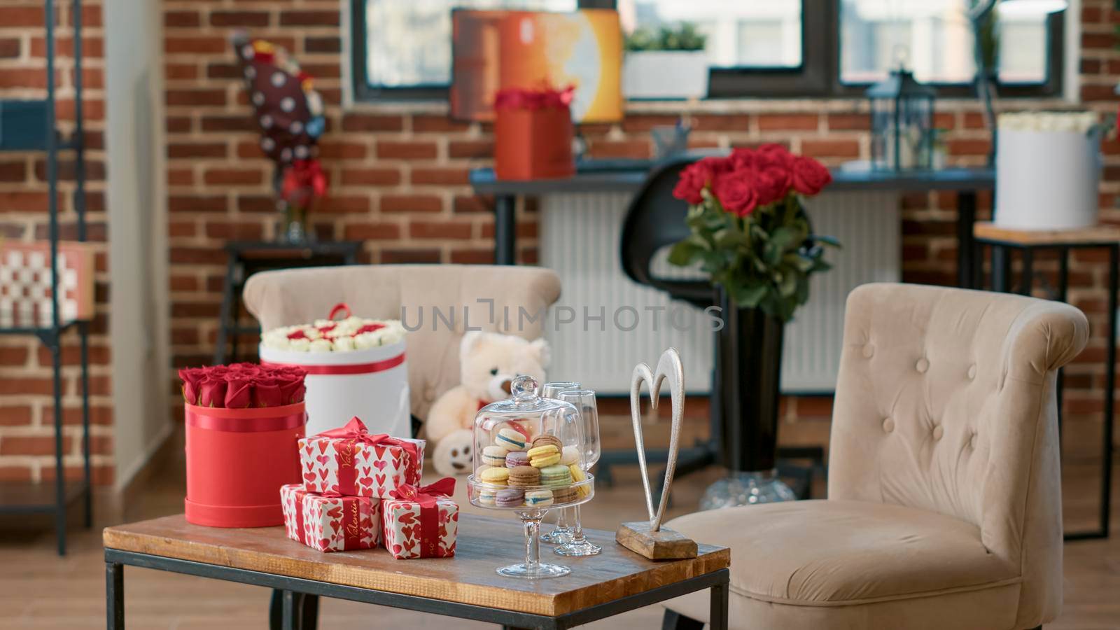 Empty living room with nobody in it having table with romantic gift and red roses on it decorated by boyfriend to celebrate valentine day at home with girlfriend. Concept of romance anniversary