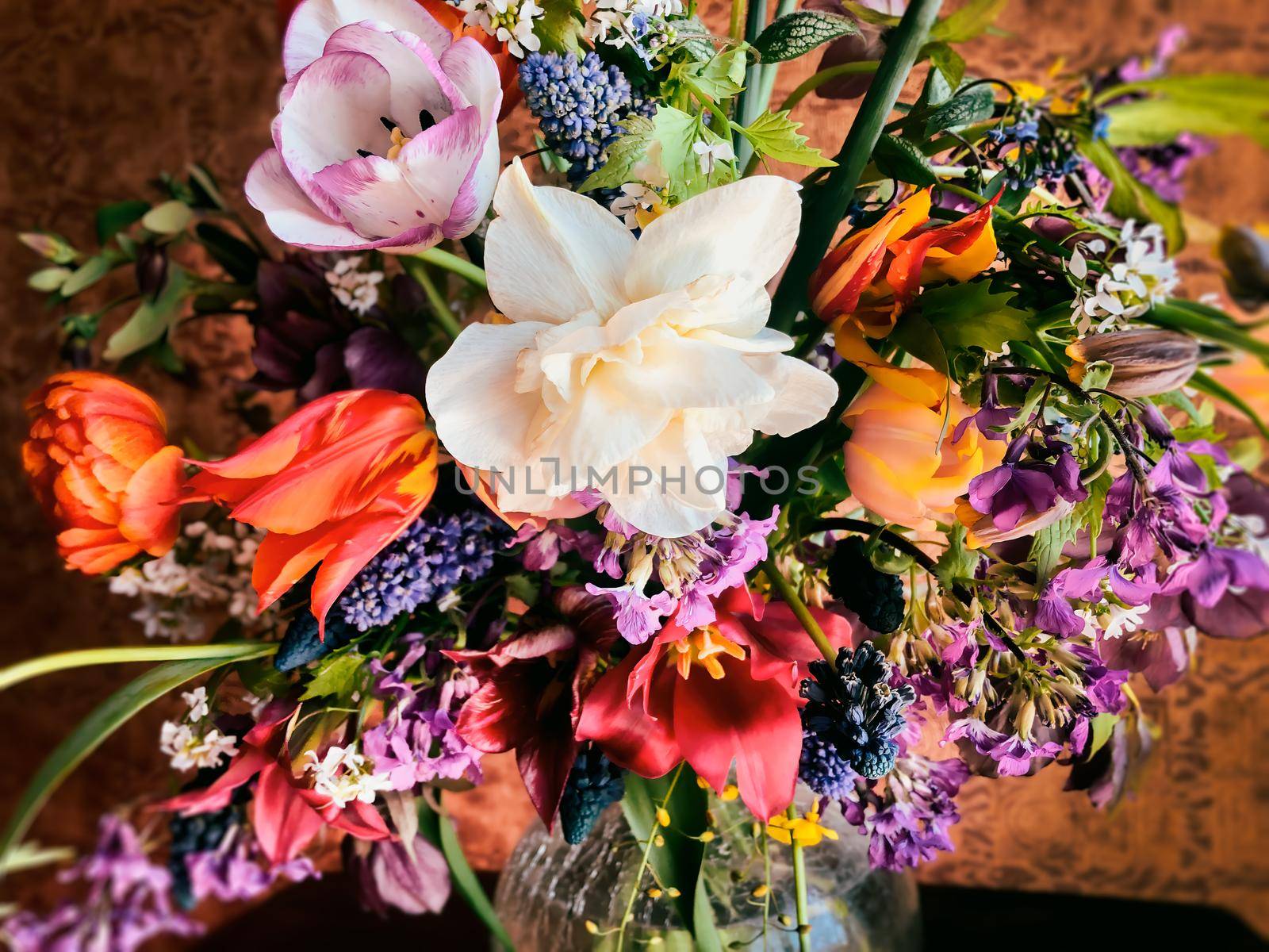 Home decor and the art of arranging bouquets. Bouquet of colorful garden flowers. The composition includes tulips, daffodils, muscari, lunaria, fritillaria and hellebore