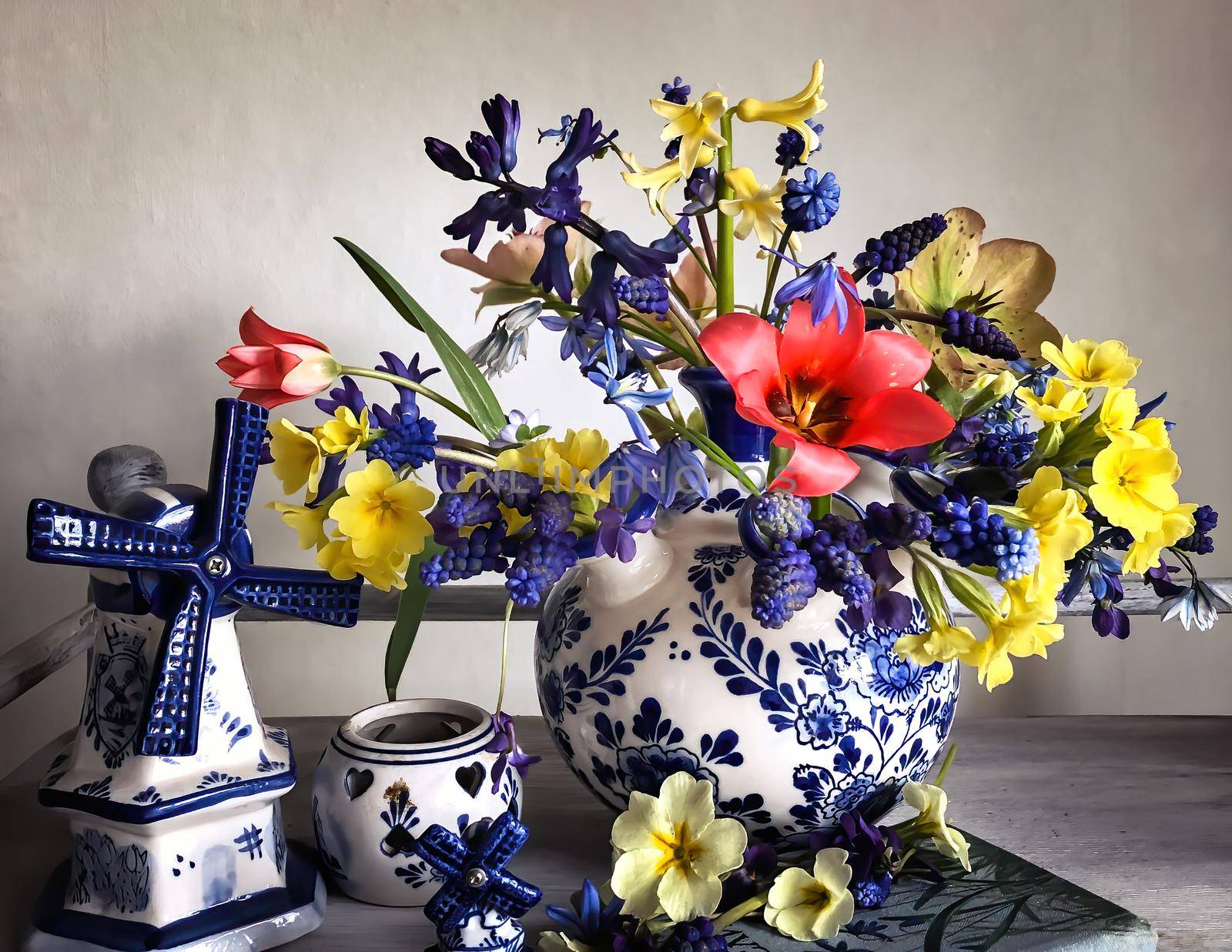 Home decor and the art of arranging bouquets. Bouquet of colorful garden flowers. The composition includes porcelain home decor, muscari, primrose, tulips and hyacinths