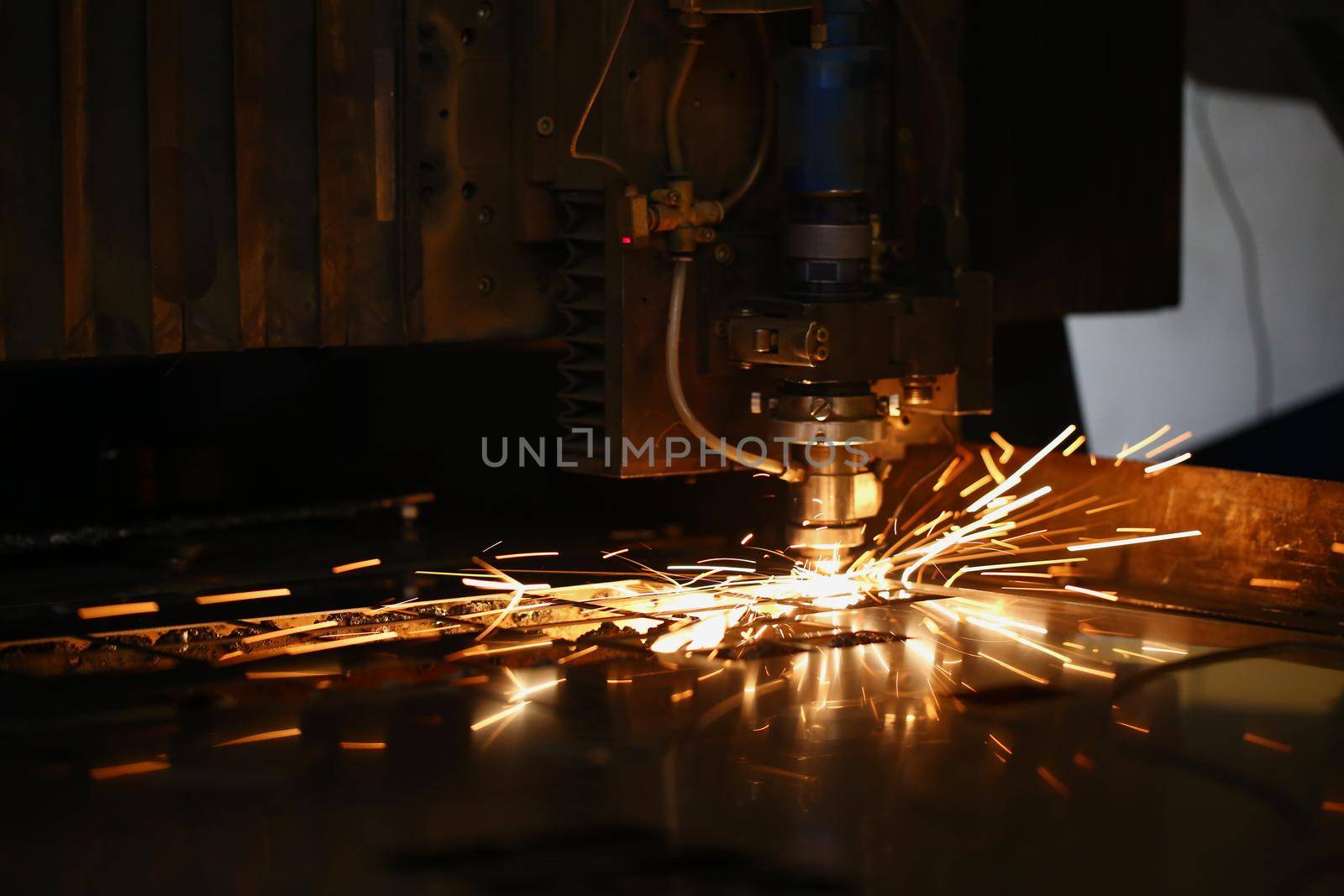 Close-up of machine head and metal processing laser metal, neon sparks fly out of it. Cutting machine and metal plate. Manufacturing, production concept