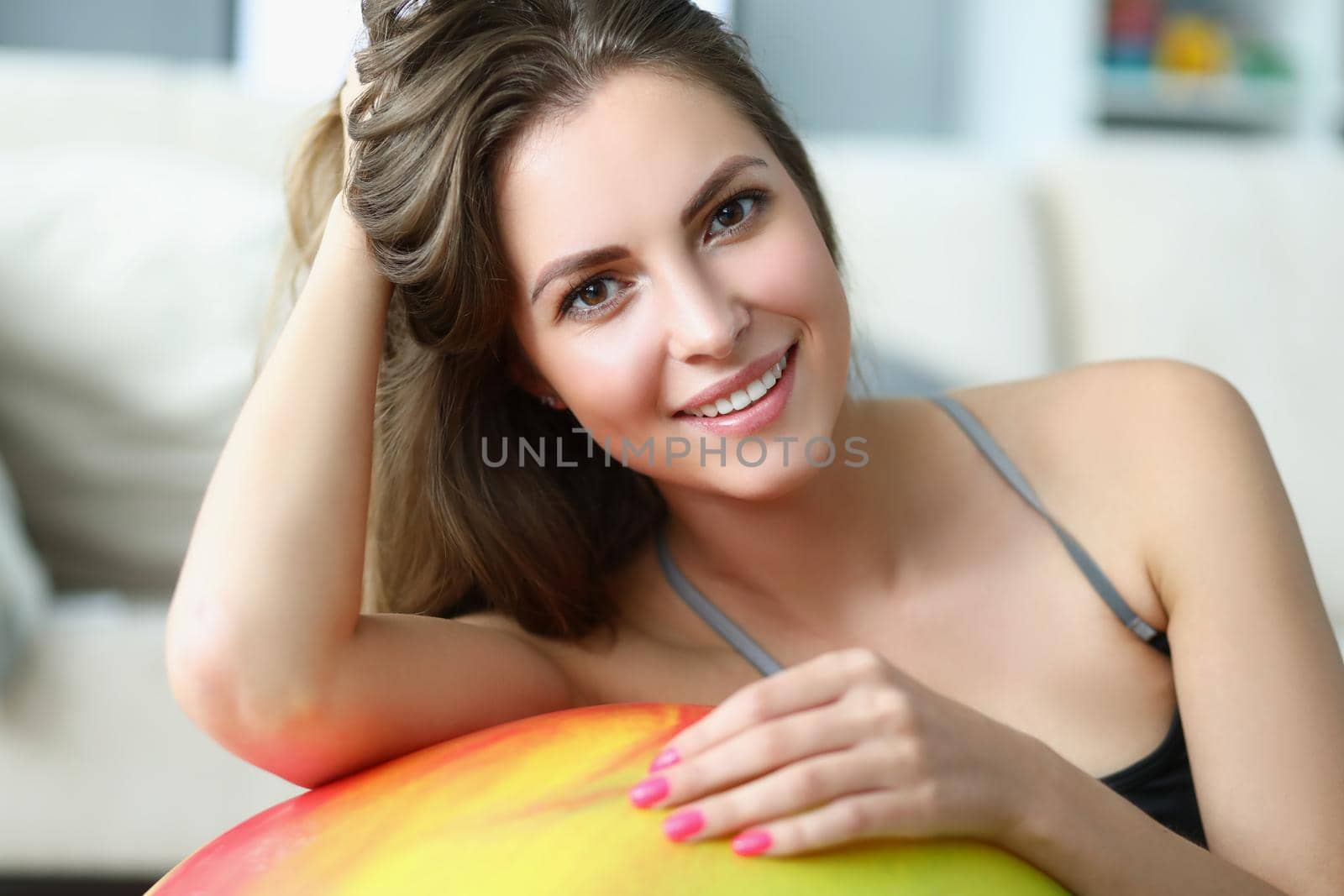 Portrait of cute brunette smiling female pose on ball, happy sportswoman. Girl prepare for active workout indoors. Sport, physical activity, train concept