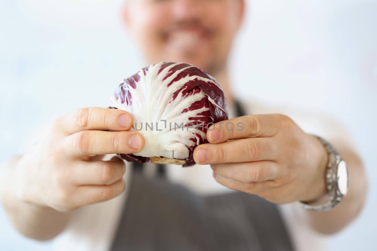 Close-up of male blogger with organic and purple vegetable in kitchen, healthy vegetarian food blog. Male with vegan ingredient. Cooking, hobby concept