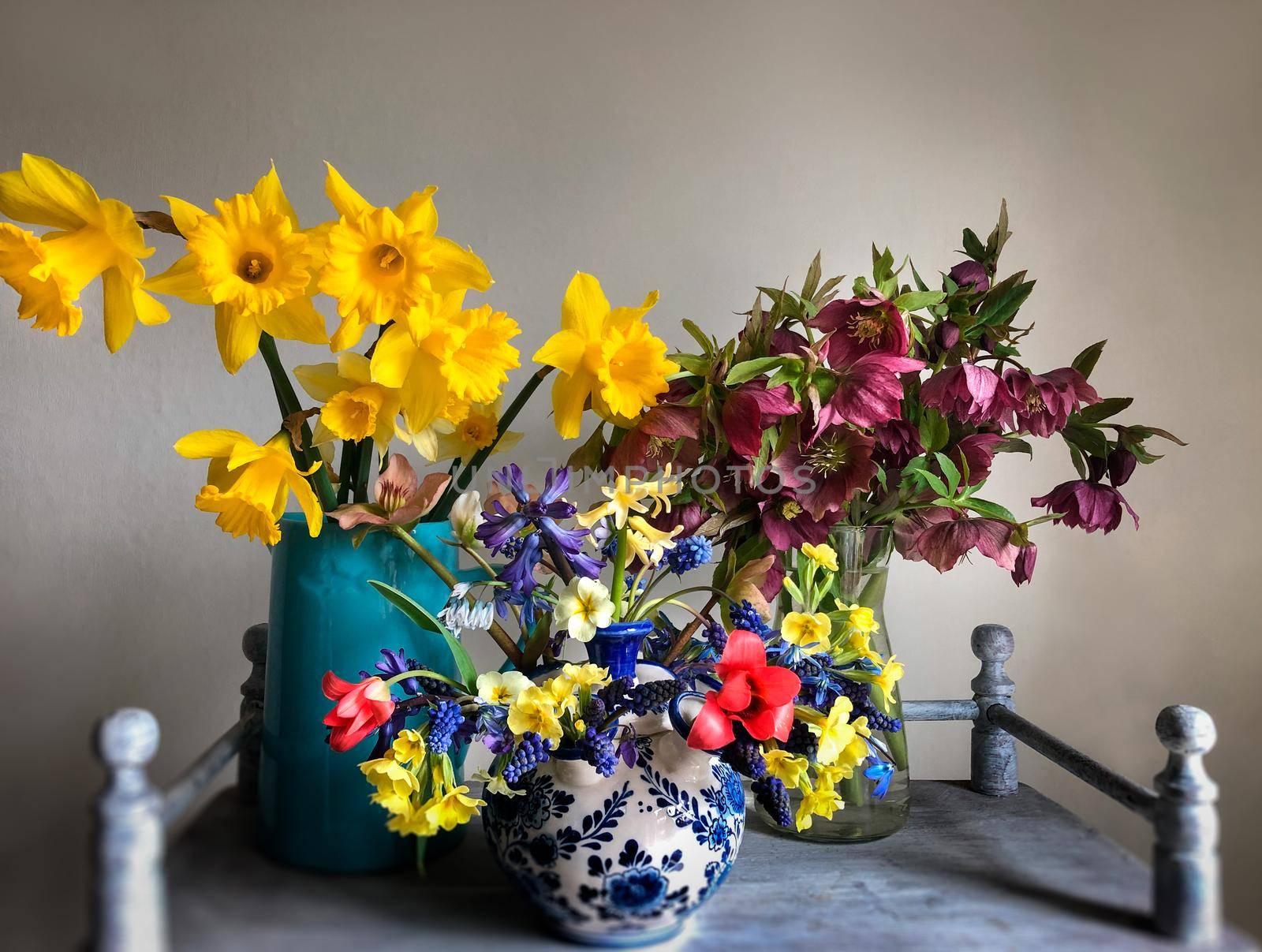 The art of flower arrangement. Romantic bouquet in retro style with flowers daffodils, hellebore, hyacinths, primrose, muscari and tulips on a vintage coffee table in the interior