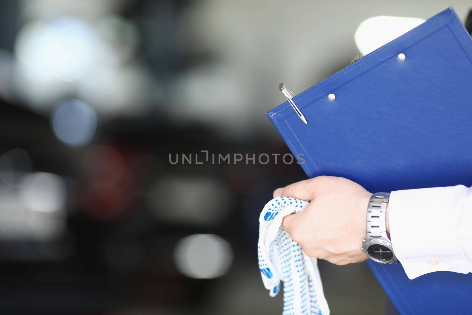 Close-up of maintenance center worker hands holding clipboard and working gloves. Cropped picture of handyman at work. Pit stop, garage, service concept