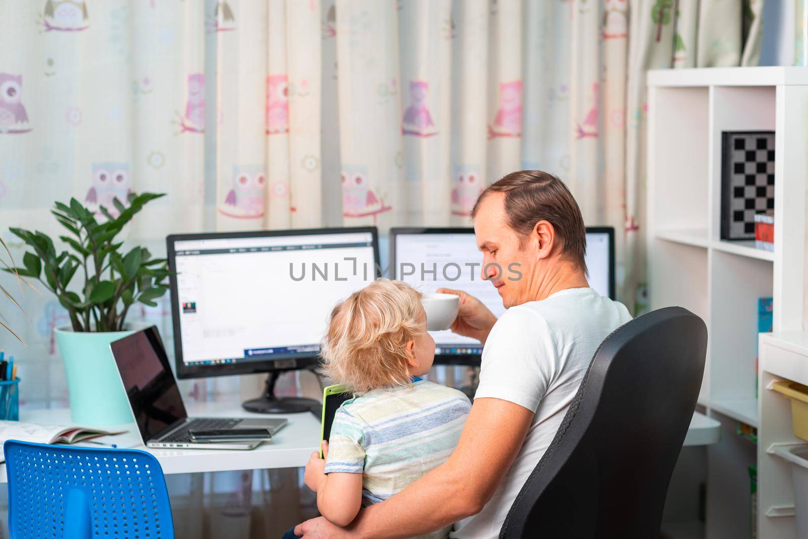 Father with kid trying to work from home during quarantine. Stay at home, work from home concept during coronavirus pandemic