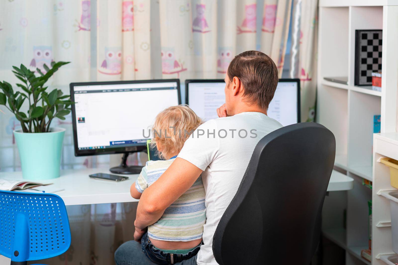 Father with kid trying to work from home during quarantine. Stay at home, work from home concept during coronavirus pandemic