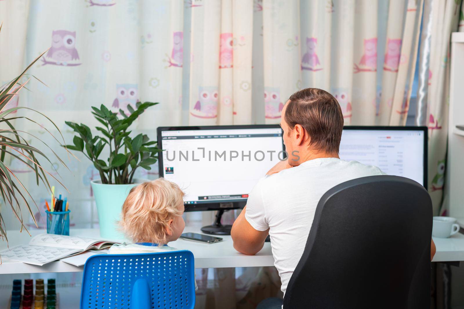 Father with kid trying to work from home during quarantine. Stay at home, work from home concept during coronavirus pandemic