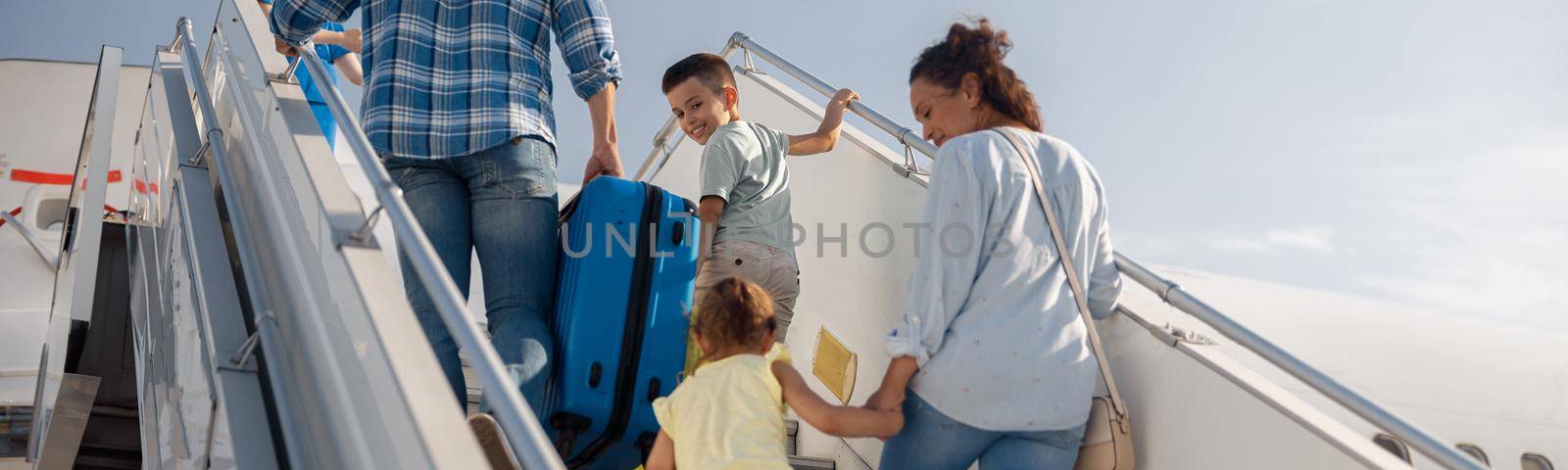 Back view of parents with two kids getting on, boarding the plane on a daytime, ready for summer vacations by Yaroslav_astakhov