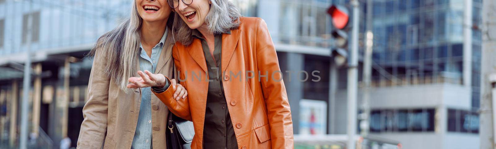 Pretty mature women with lot of shopping bags laugh on city street by Yaroslav_astakhov