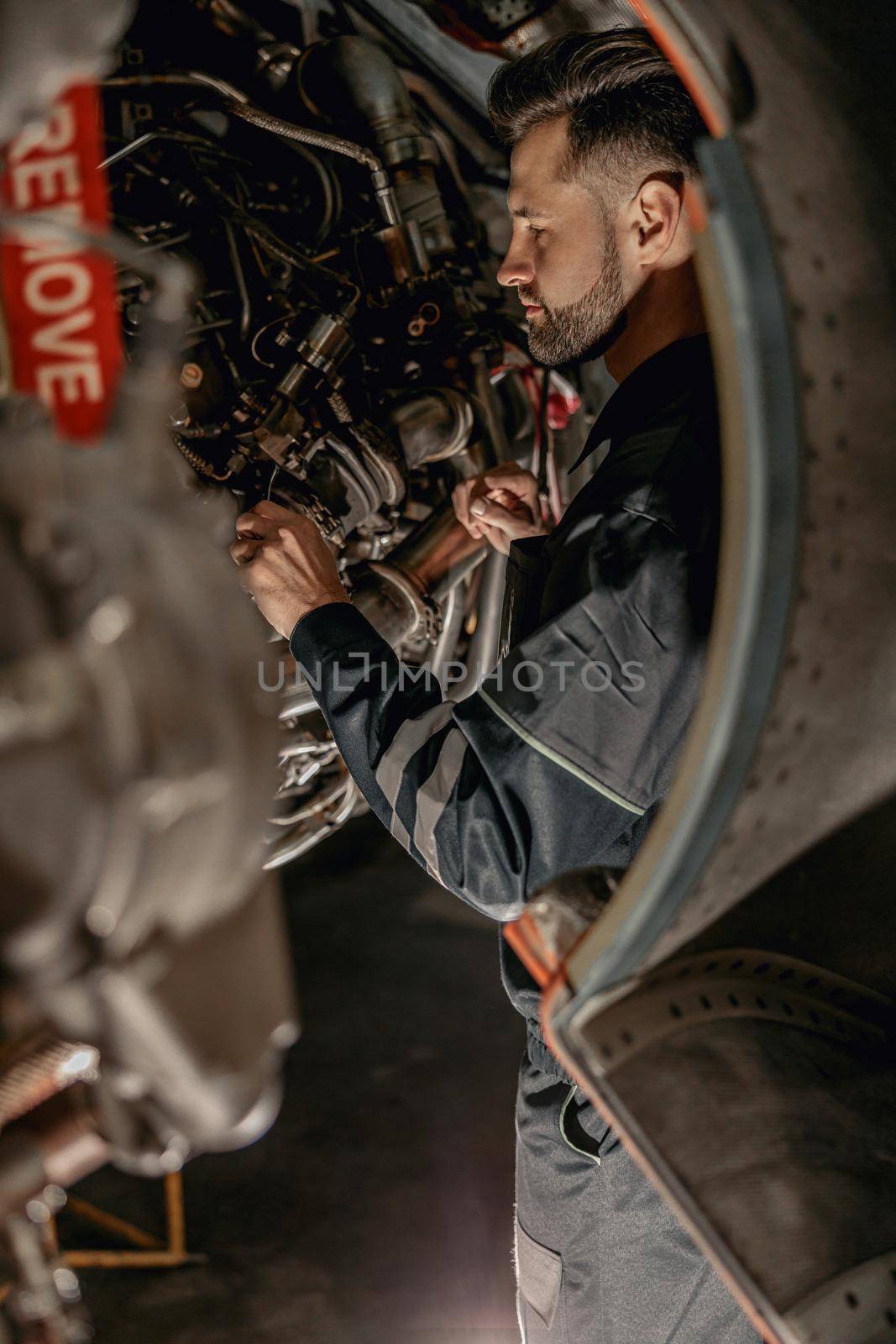 Male airline mechanic repairing aircraft in hangar by Yaroslav_astakhov