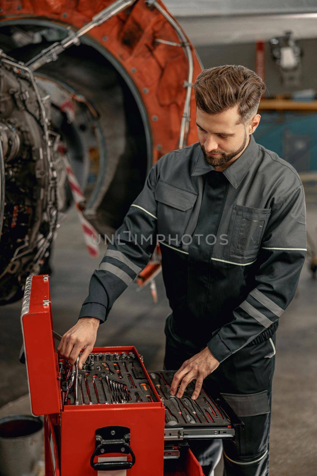 Bearded man aircraft mechanic using tool box in hangar by Yaroslav_astakhov