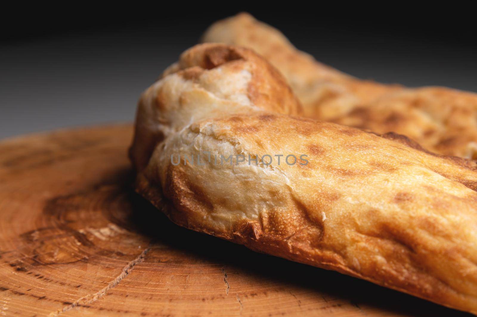 Close-up fried khachapuri cooked in the oven lies on a wooden board by yanik88
