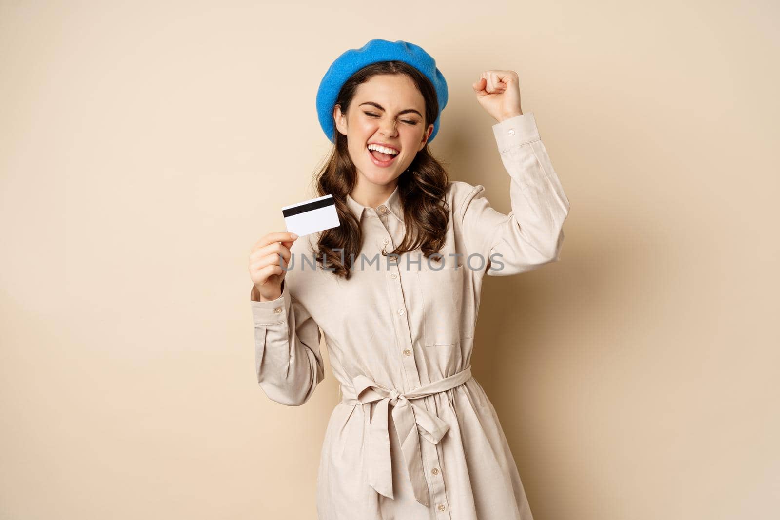 Enthusiastic young woman yearning to go shopping, dancing with credit card and celebrating, laughing and smiling by Benzoix