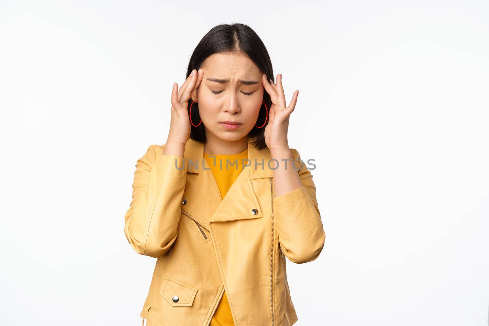 Image of asian woman massaging head temples with concerned face, suffering headache, migraine, standing over white background.