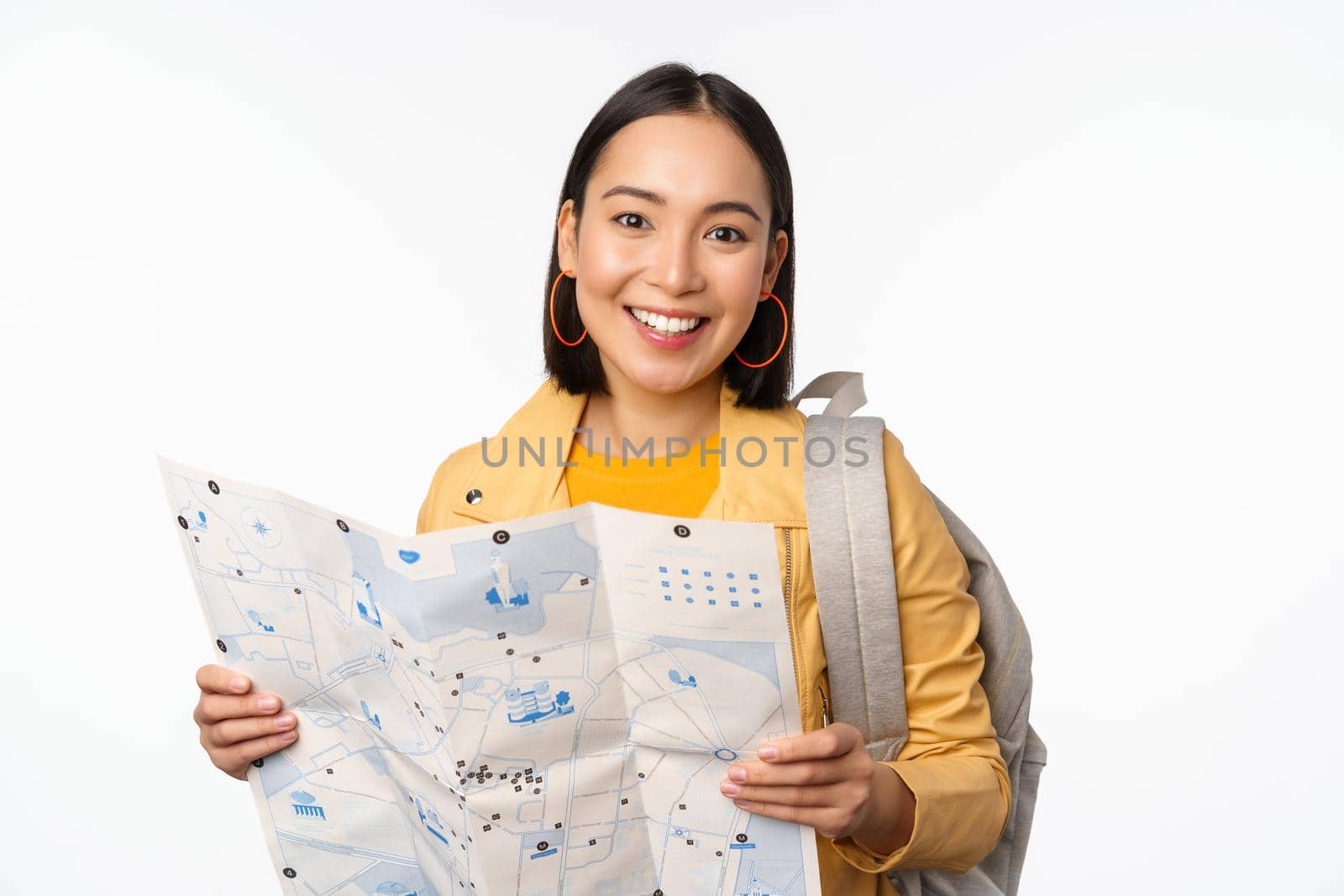 Tourism and backpacking. Smiling asian girl holding map and backpack, tourist searching way, travelling, standing over white background.