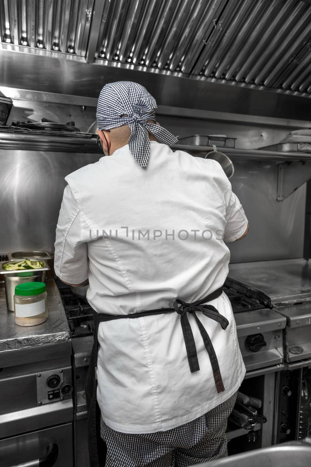 Back view of woman chef cooking food in the kitchen of a restaurant. by HERRAEZ