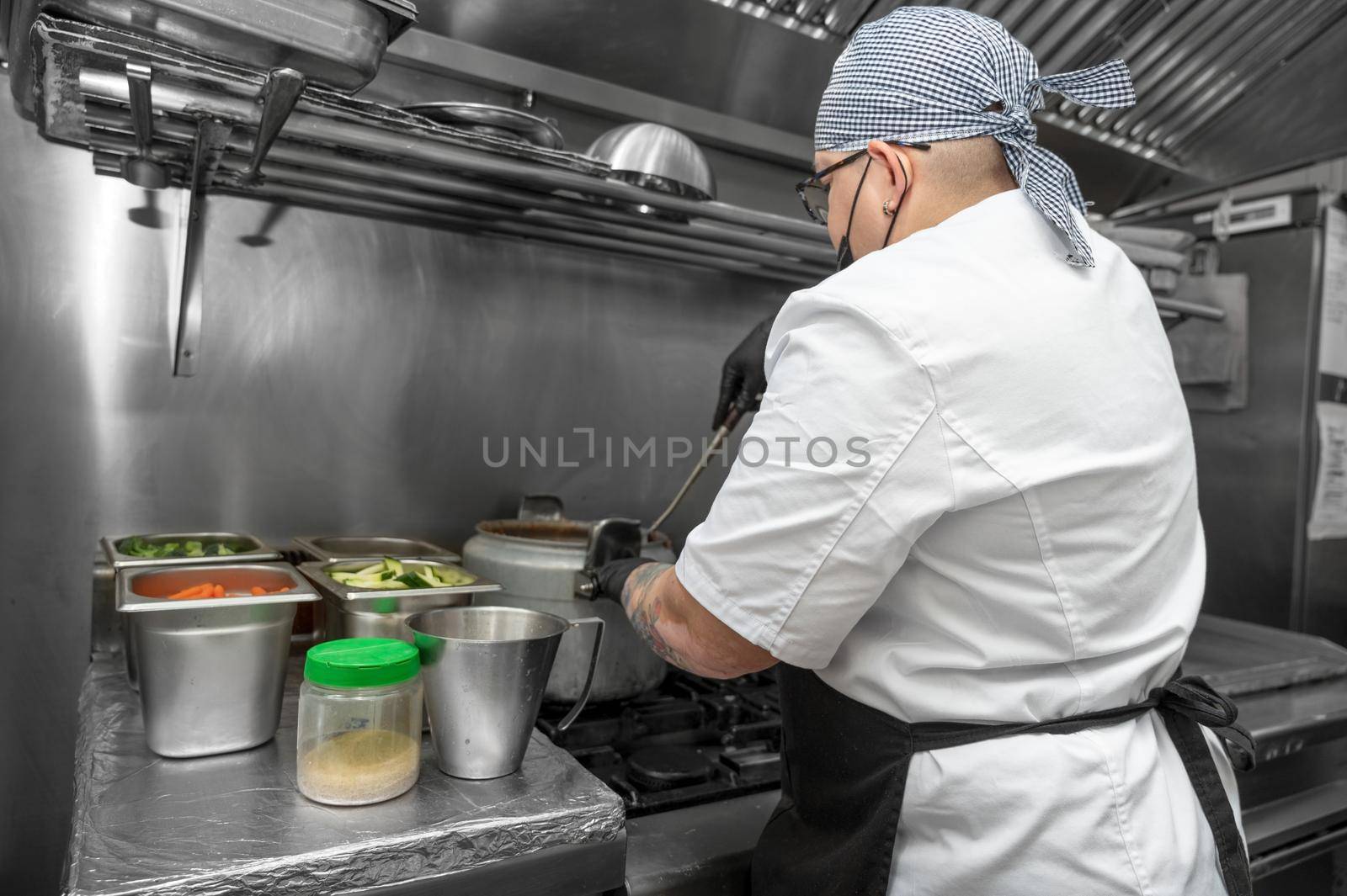 Side view of female chef working in commercial kitchen by HERRAEZ