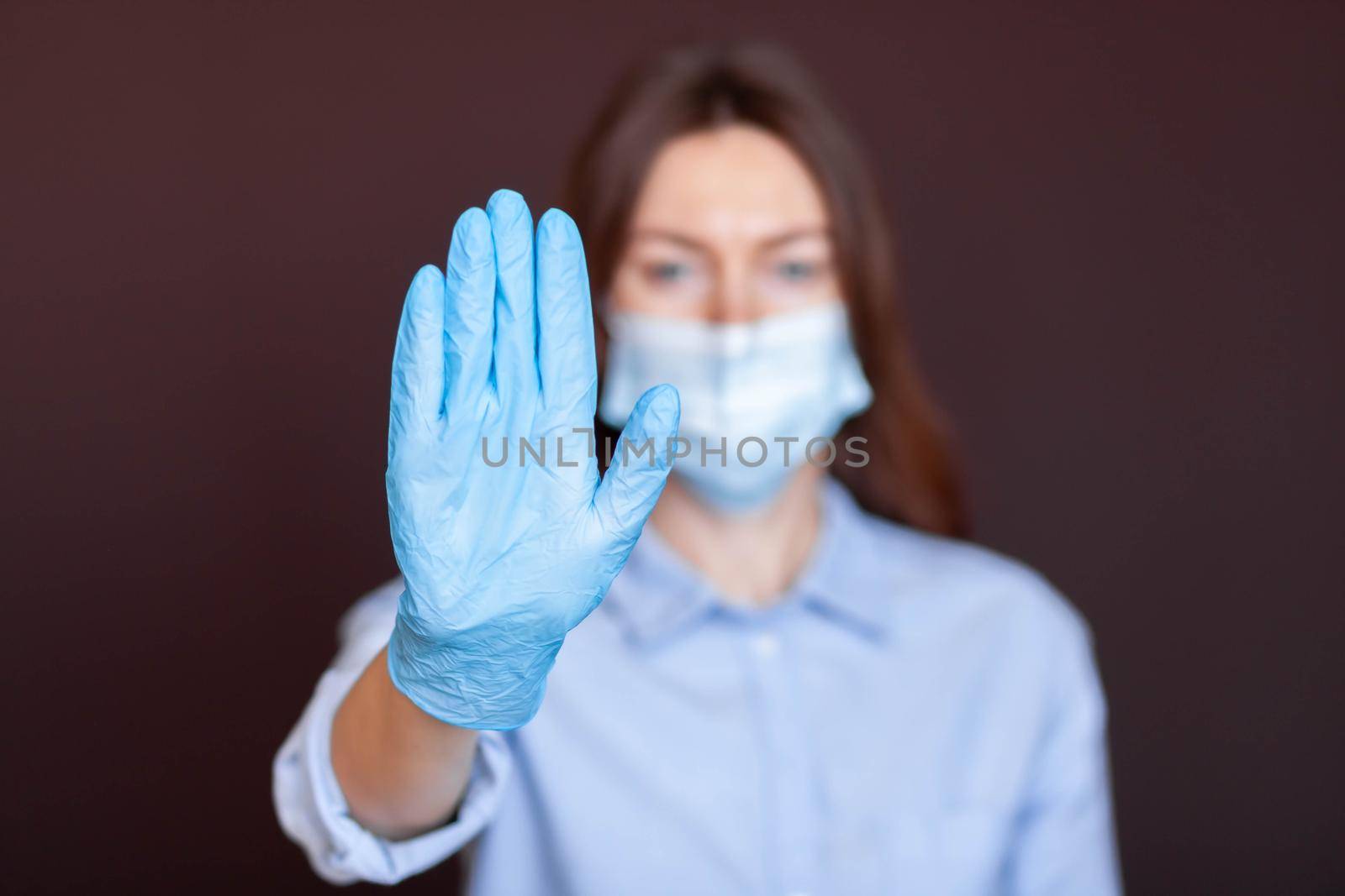 Coronavirus concept. Girl wearing mask for protection from disease and show stop hands gesture for stop corona virus outbreak. Global call to stay home. Stop the pandemic with vaccination