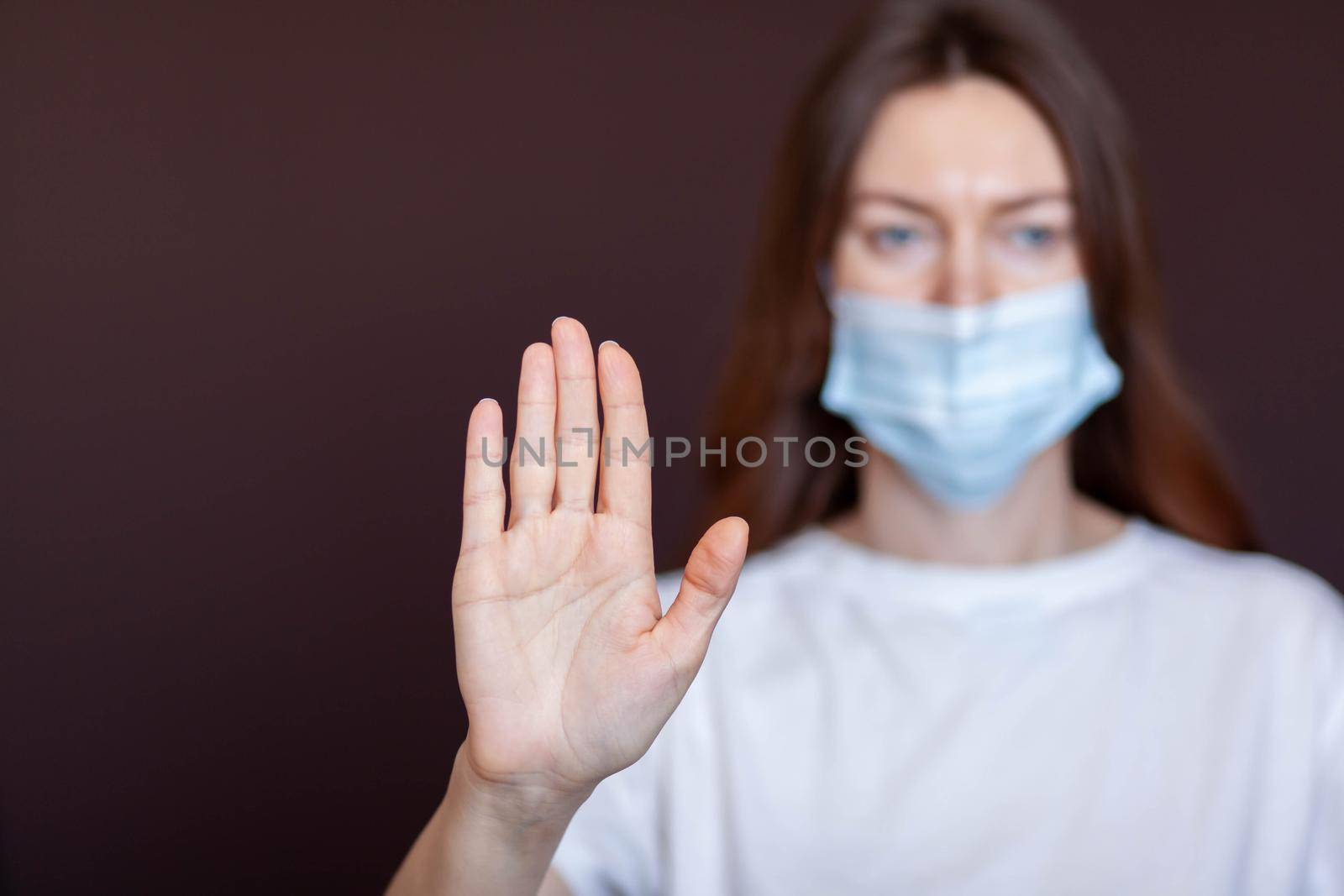 Coronavirus concept. Girl wearing mask for protection from disease and show stop hands gesture for stop corona virus outbreak. Global call to stay home. Stop the pandemic with vaccination