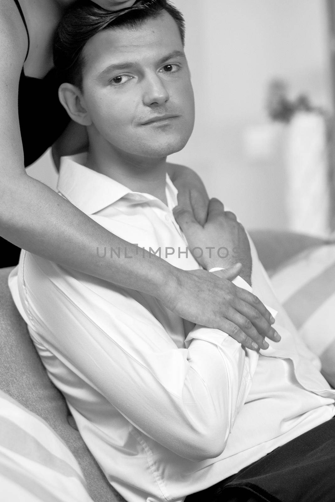 Love and passion woman hugs man. Husband and wife after a romantic dinner. Romance in relationships, love and tenderness. Beautiful young couple in home interior. Black and white photo by LipikStockMedia